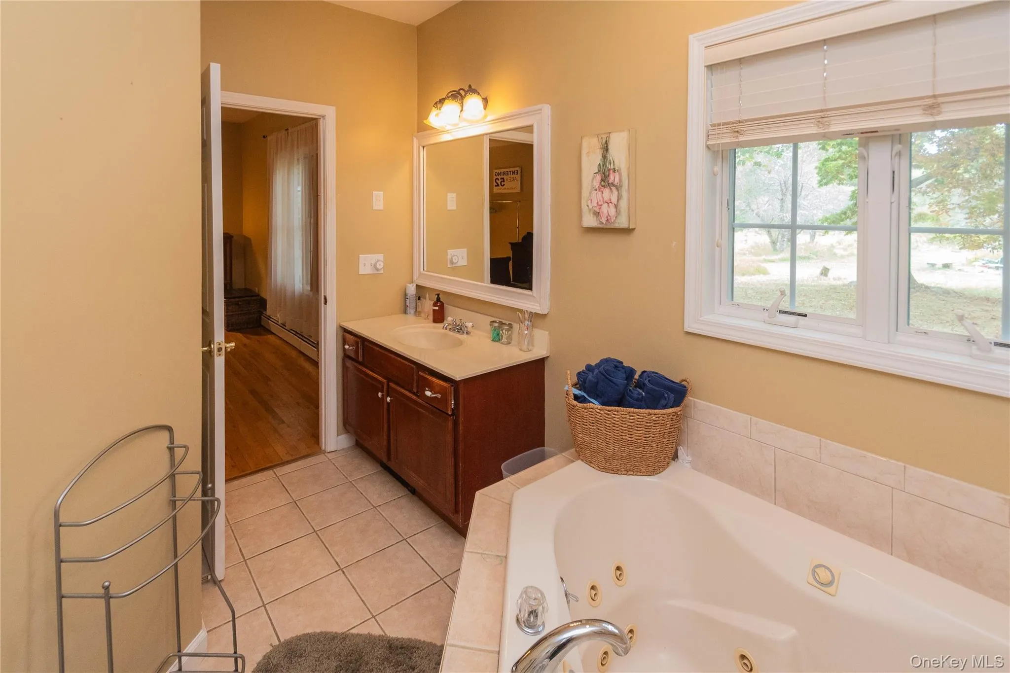 Full bath featuring vanity, a whirlpool tub, baseboard heating, and light tile patterned floors Full bath featuring vanity, a whirlpool tub, baseboard heating, and light tile patterned floors