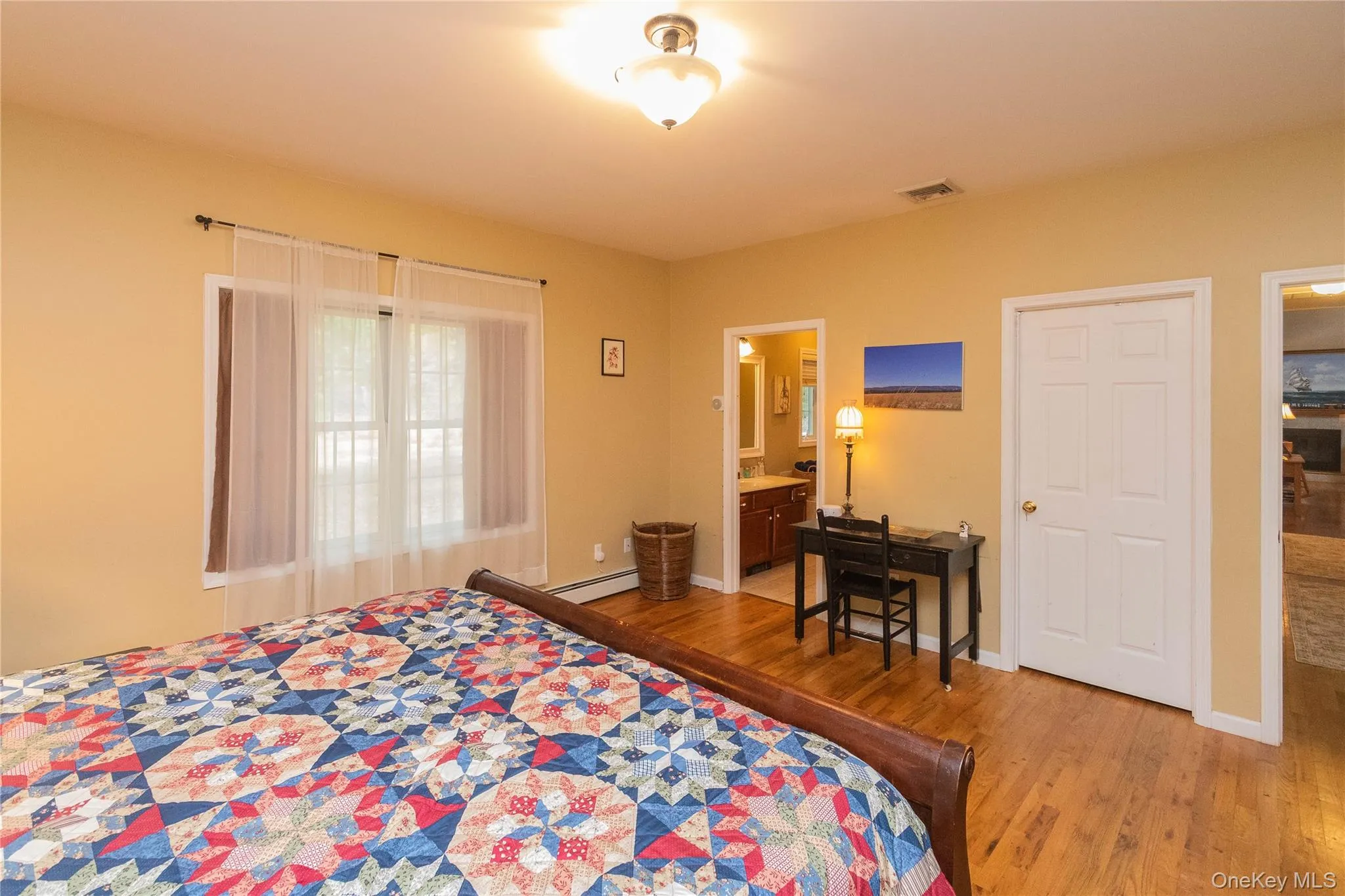 Bedroom with light wood-type flooring, a baseboard heating unit, and ensuite bathroom Bedroom with light wood-type flooring, a baseboard heating unit, and ensuite bathroom