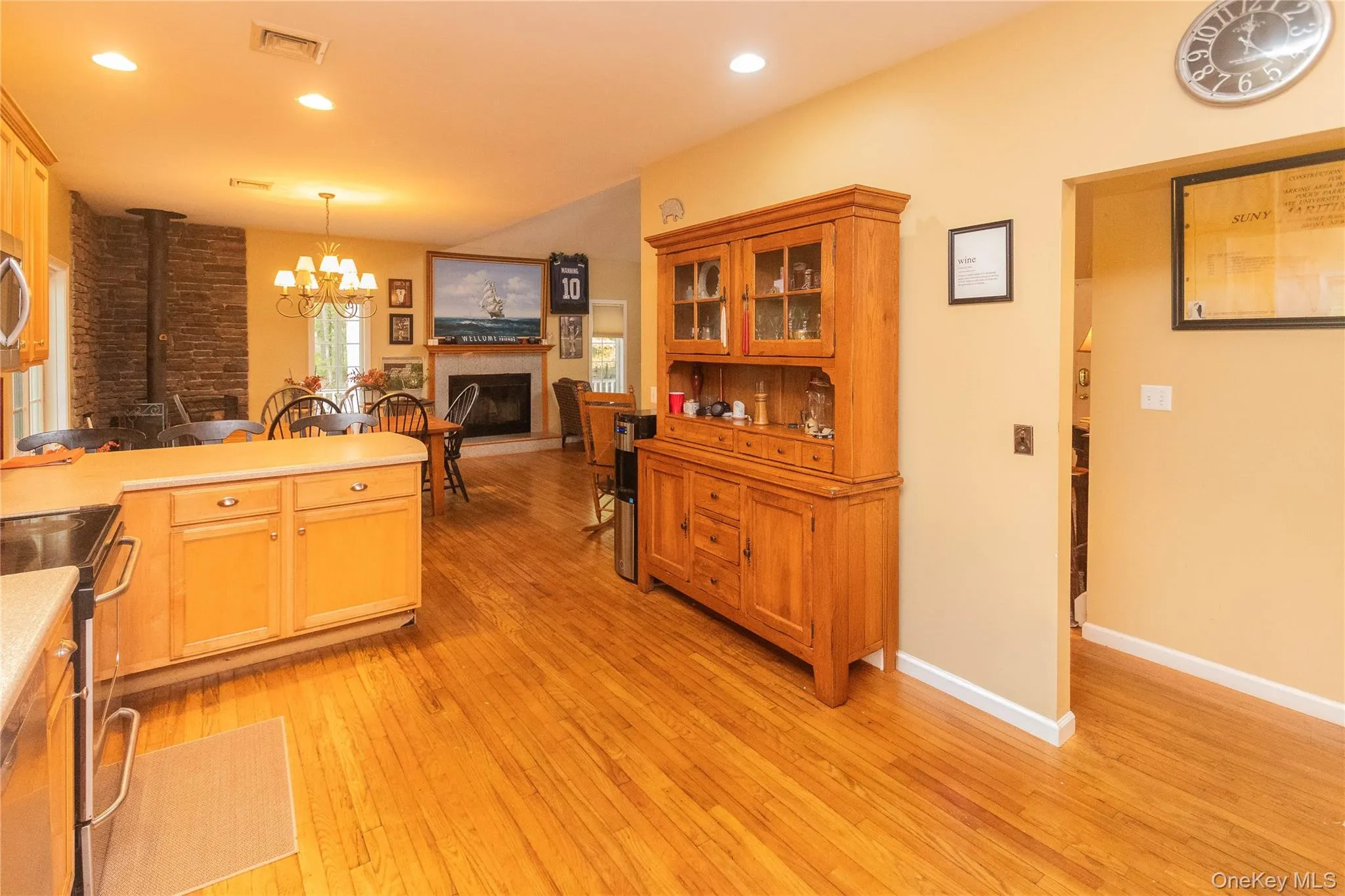 Kitchen with appliances with stainless steel finishes, a wood stove, light wood-style floors, light countertops, and glass insert cabinets Kitchen with appliances with stainless steel finishes, a wood stove, light wood-style floors, light countertops, and glass insert cabinets