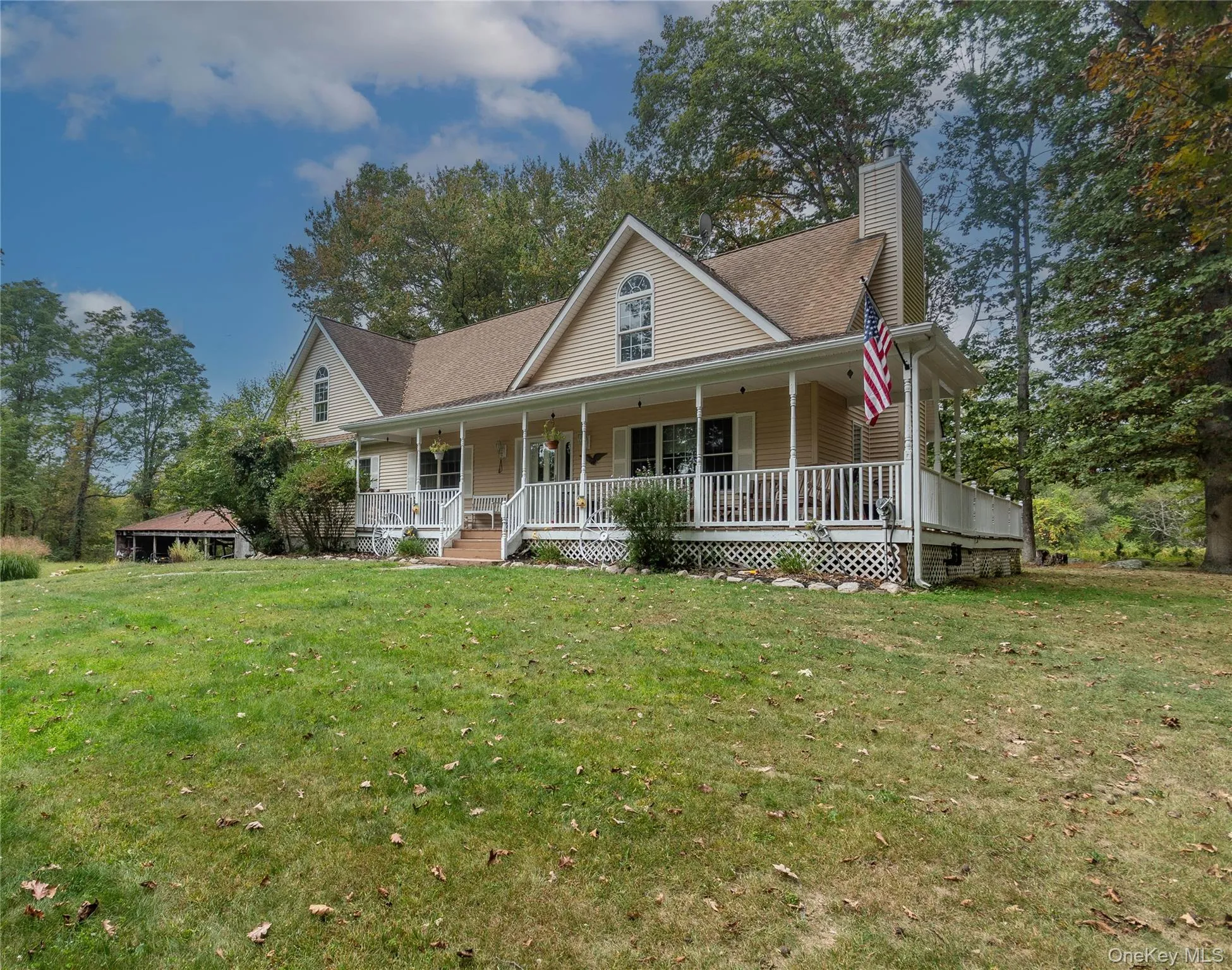 Farmhouse inspired home featuring a chimney, a porch, a front yard, and a shingled roof Farmhouse inspired home featuring a chimney, a porch, a front yard, and a shingled roof