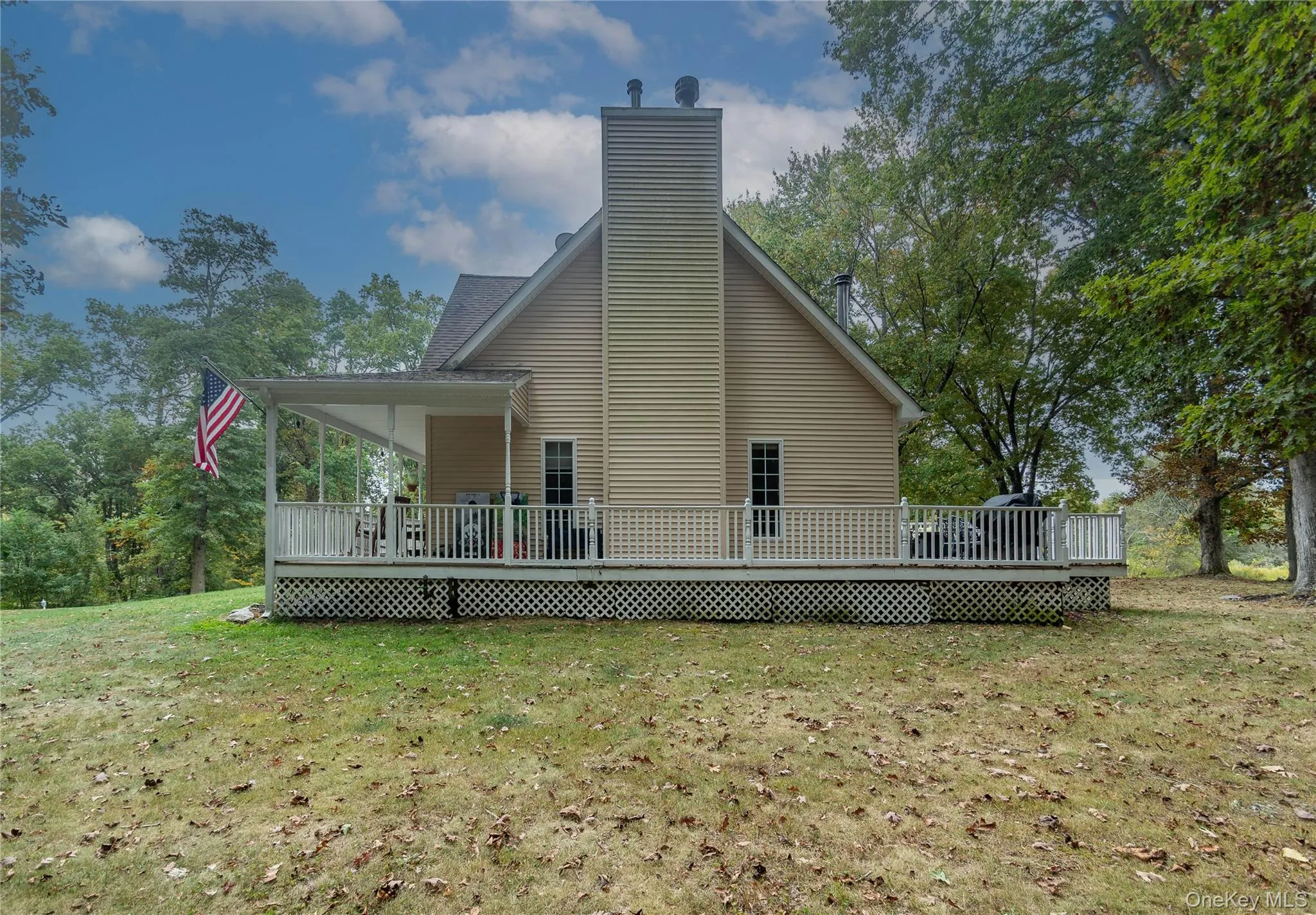 Back of house with a lawn, a chimney, and a deck Back of house with a lawn, a chimney, and a deck