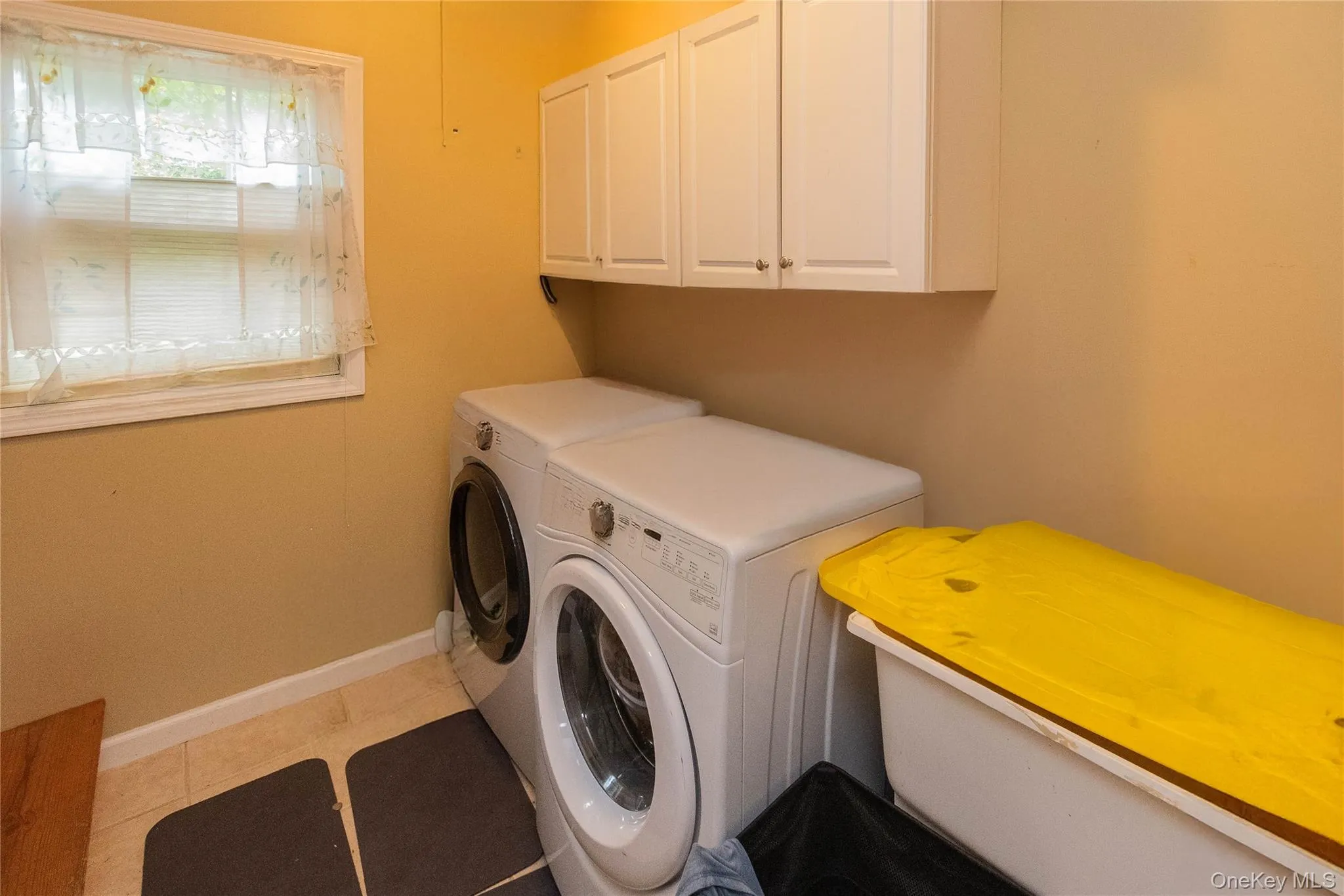 Laundry area featuring independent washer and dryer, light tile patterned flooring, and cabinet space Laundry area featuring independent washer and dryer, light tile patterned flooring, and cabinet space