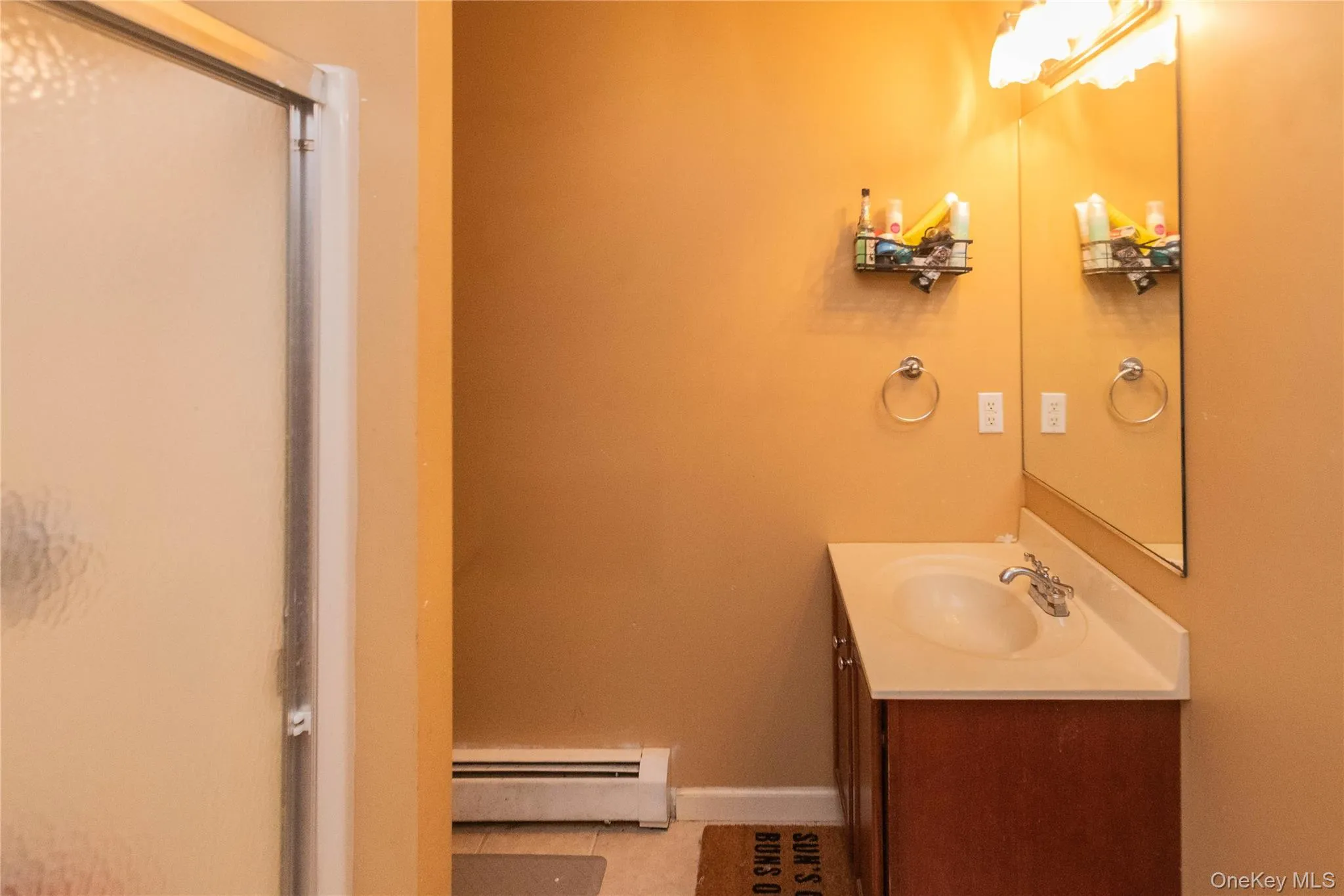 Bathroom with vanity, a baseboard heating unit, light tile patterned flooring, and a stall shower Bathroom with vanity, a baseboard heating unit, light tile patterned flooring, and a stall shower