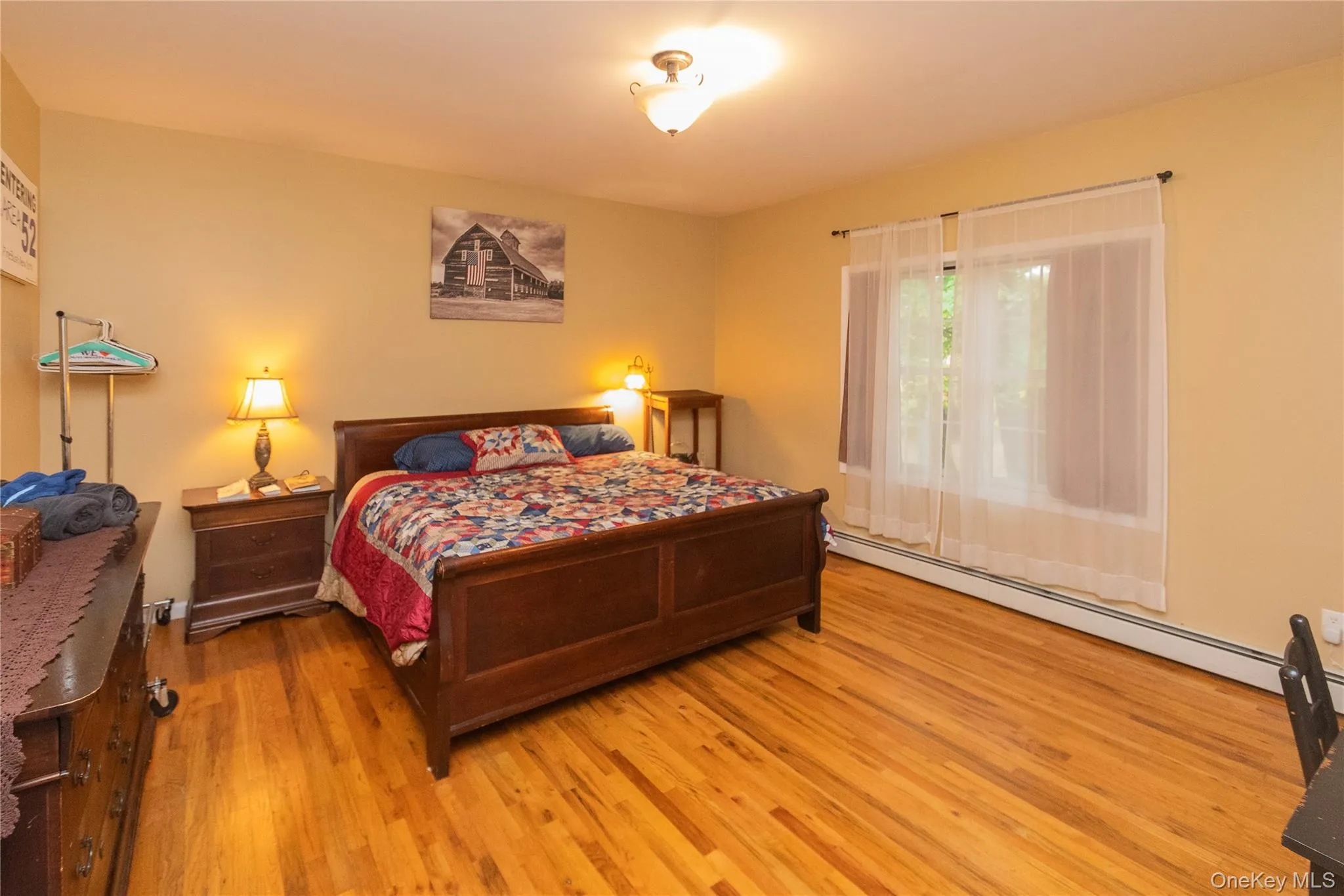 Bedroom with wood finished floors and a baseboard heating unit Bedroom with wood finished floors and a baseboard heating unit