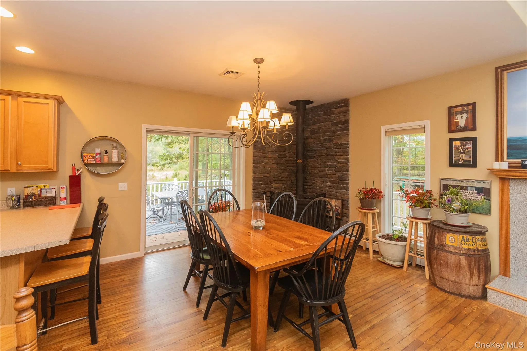 Dining area featuring light wood finished floors, a chandelier, and a wood stove Dining area featuring light wood finished floors, a chandelier, and a wood stove