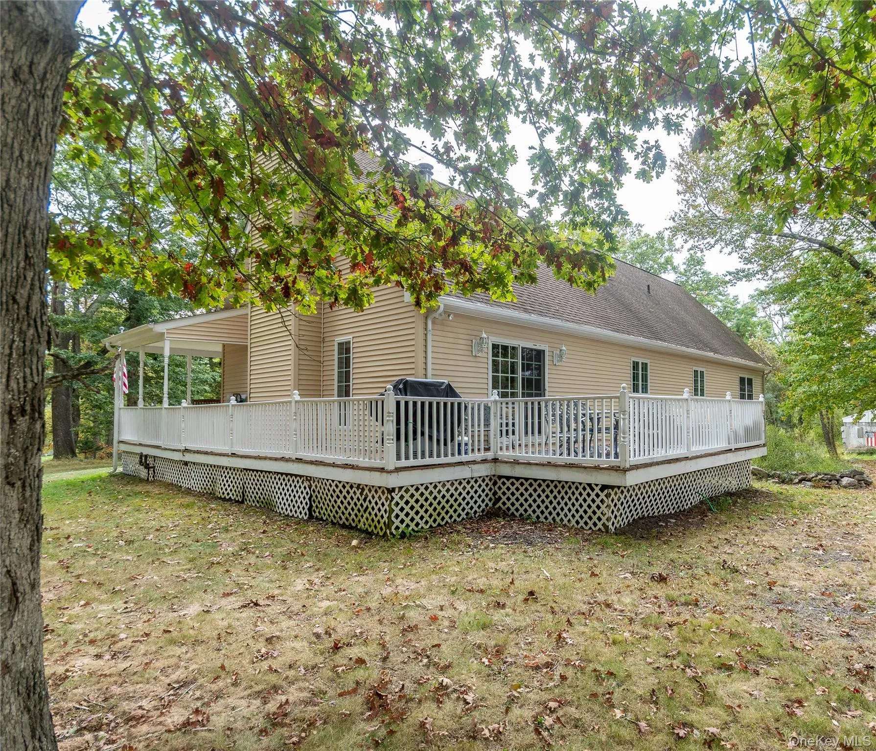 Back of property featuring a wooden deck, a yard, and a shingled roof Back of property featuring a wooden deck, a yard, and a shingled roof