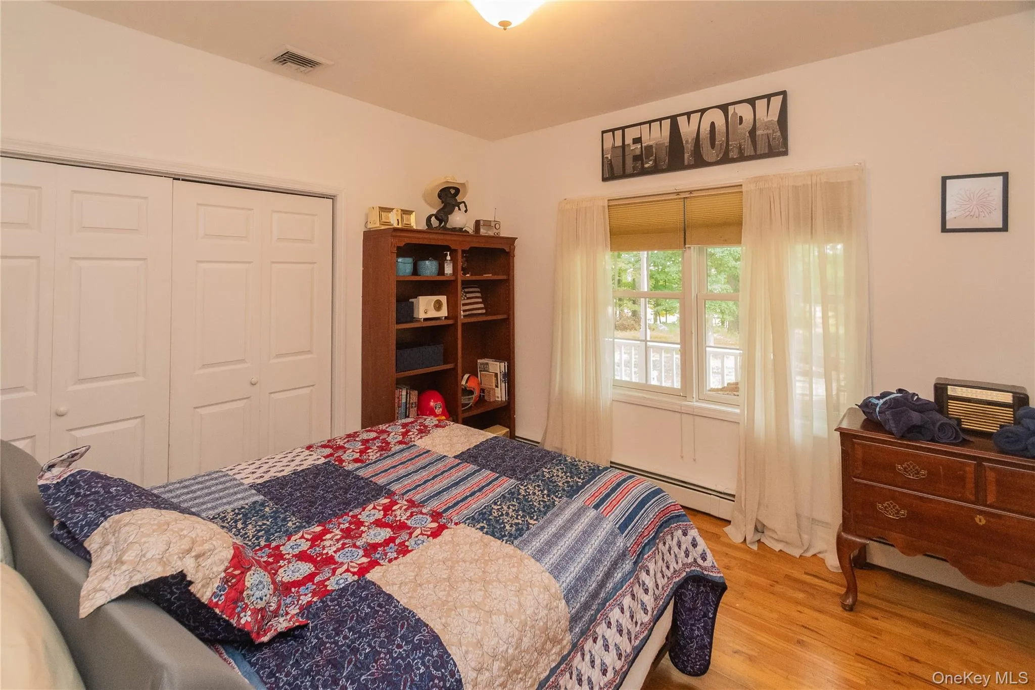 Bedroom with light wood finished floors, a baseboard heating unit, and a closet Bedroom with light wood finished floors, a baseboard heating unit, and a closet