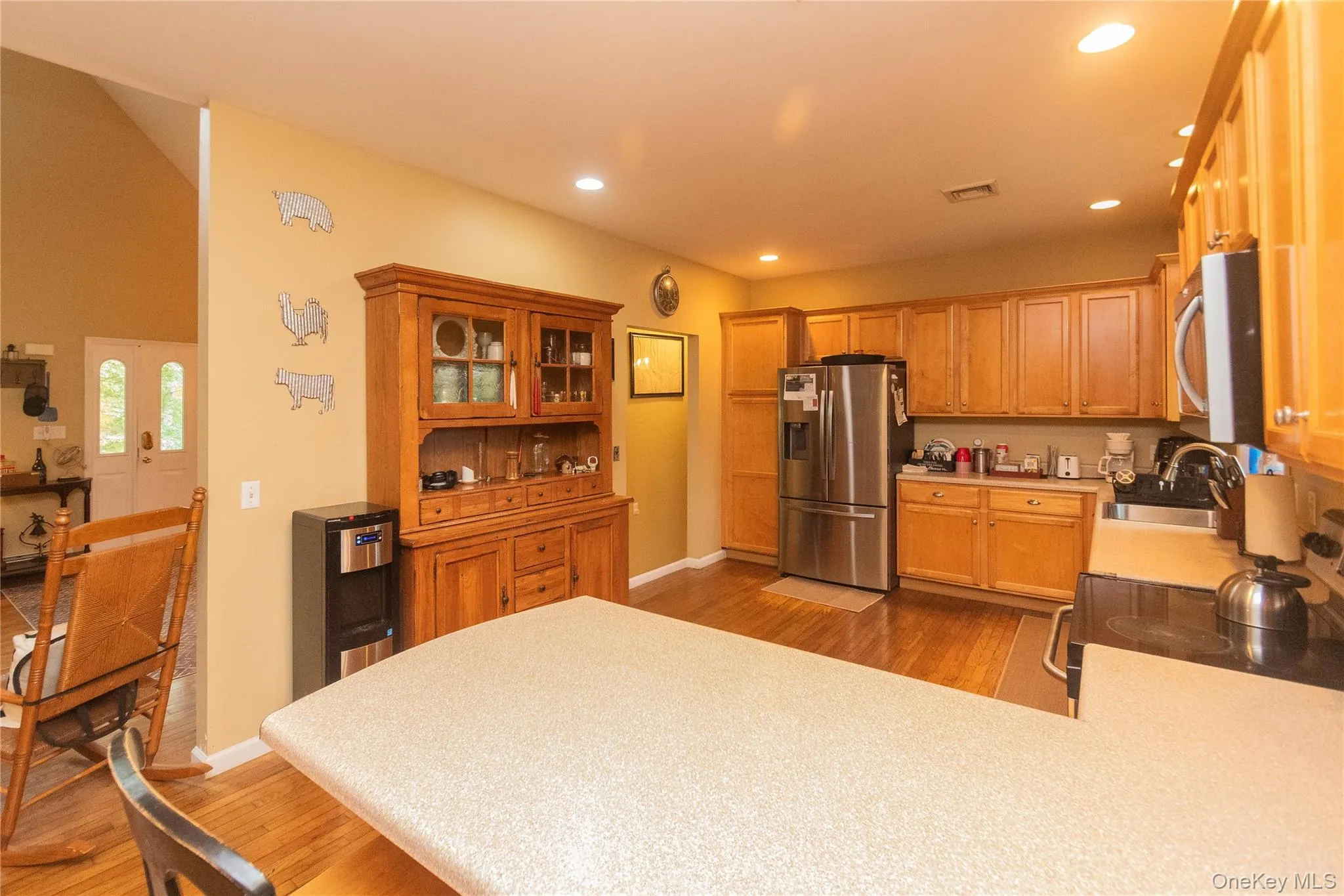 Kitchen with appliances with stainless steel finishes, light wood-style flooring, glass insert cabinets, light countertops, and recessed lighting Kitchen with appliances with stainless steel finishes, light wood-style flooring, glass insert cabinets, light countertops, and recessed lighting