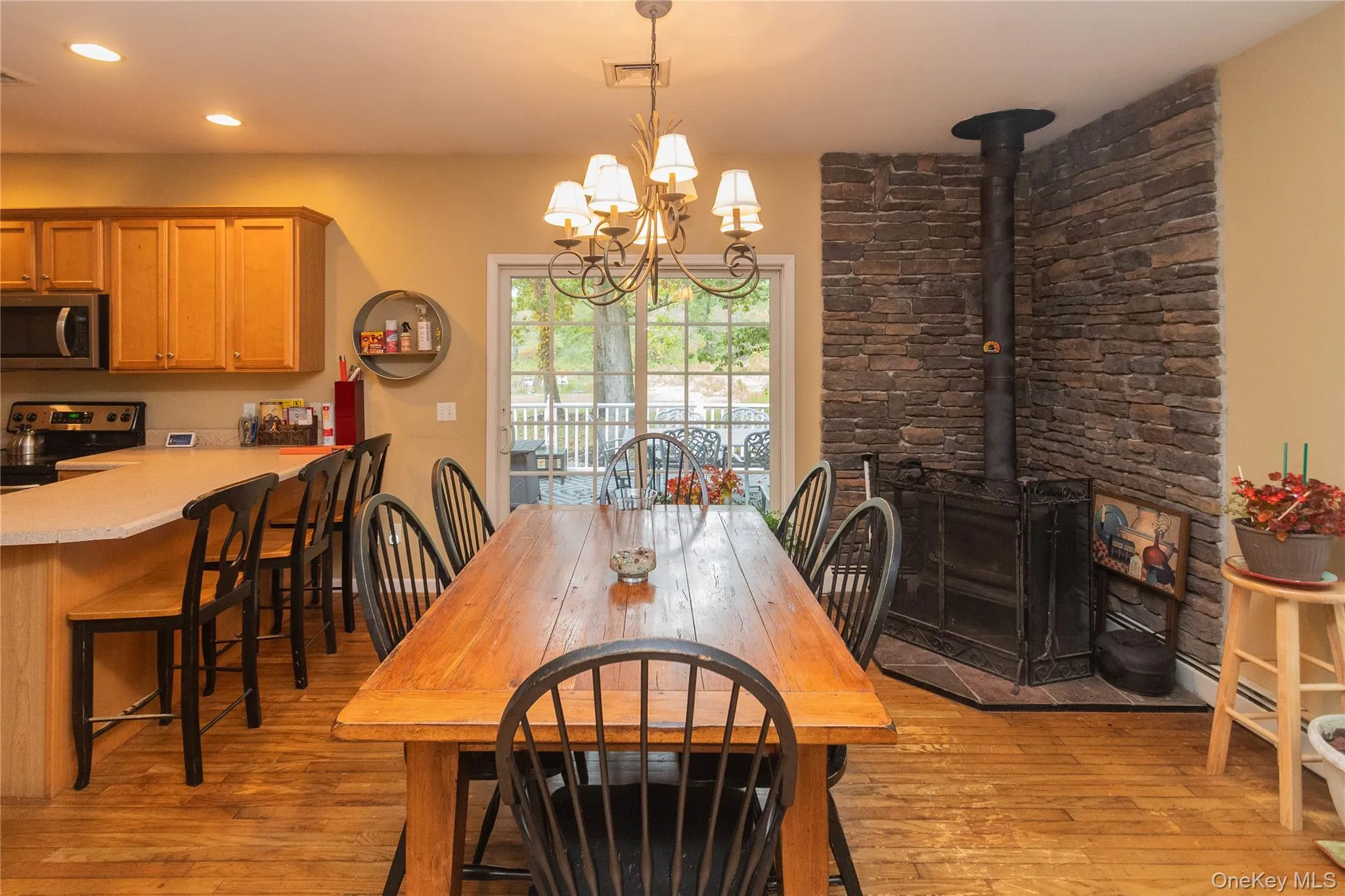 Dining room featuring a wood stove, light wood-type flooring, a chandelier, and recessed lighting Dining room featuring a wood stove, light wood-type flooring, a chandelier, and recessed lighting