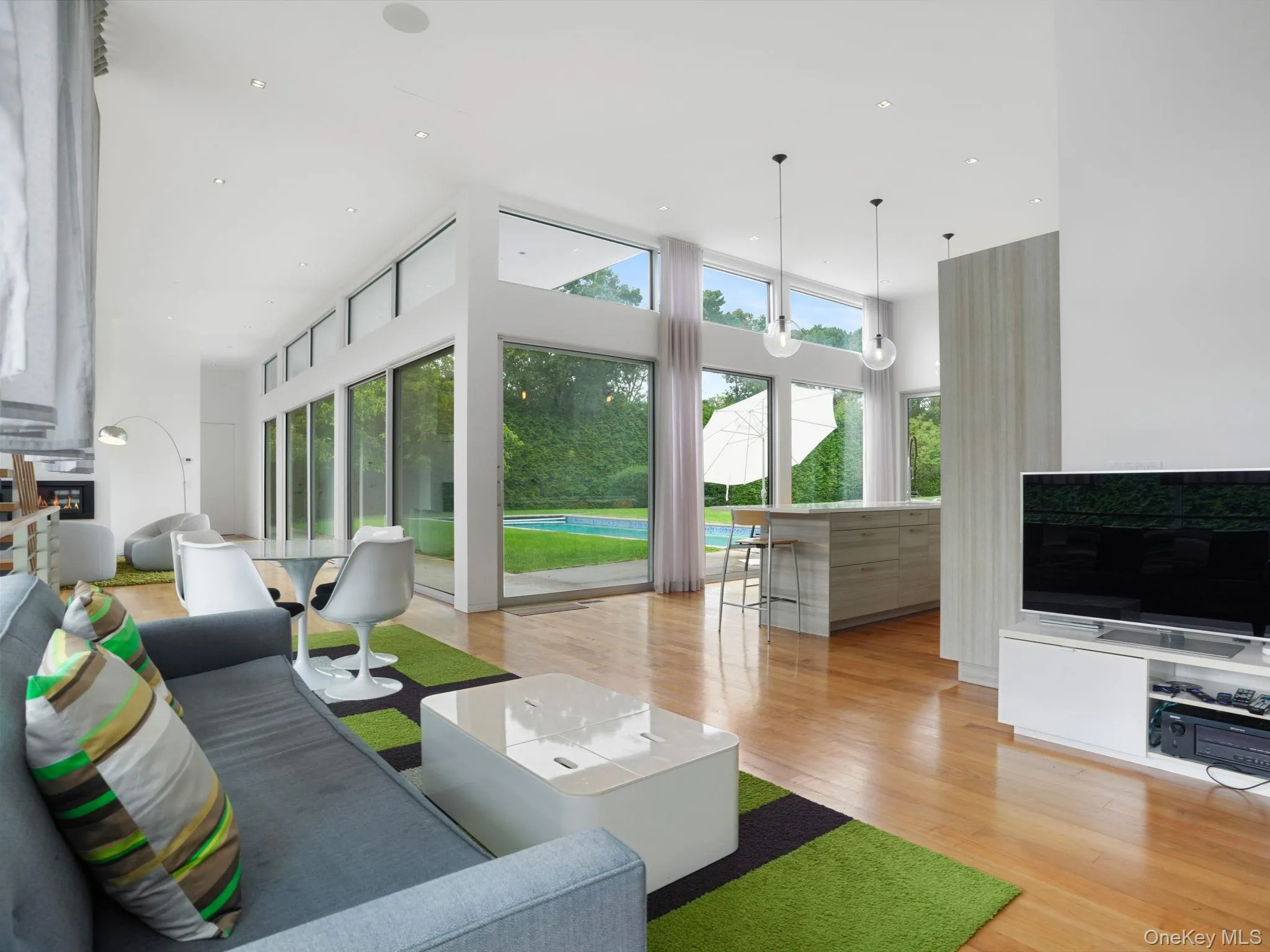 Living area with a high ceiling, light wood-type flooring, and recessed lighting Living area with a high ceiling, light wood-type flooring, and recessed lighting