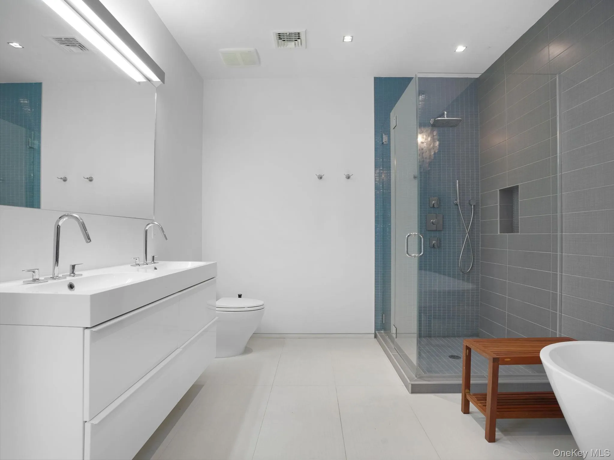 Bathroom with a stall shower, double vanity, a freestanding tub, light tile patterned floors, and recessed lighting Bathroom with a stall shower, double vanity, a freestanding tub, light tile patterned floors, and recessed lighting