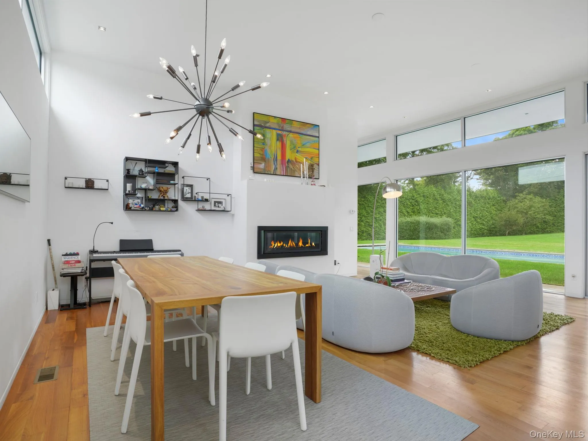 Dining area with a glass covered fireplace, a high ceiling, wood finished floors, a chandelier, and recessed lighting Dining area with a glass covered fireplace, a high ceiling, wood finished floors, a chandelier, and recessed lighting