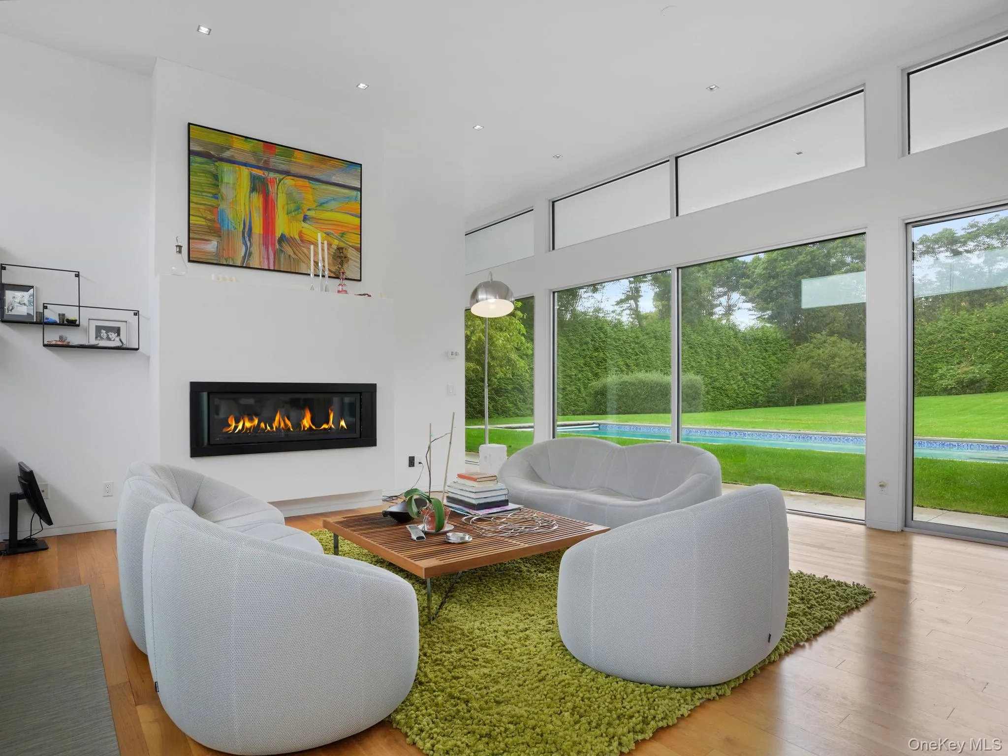 Living room with a glass covered fireplace, light wood finished floors, and recessed lighting Living room with a glass covered fireplace, light wood finished floors, and recessed lighting