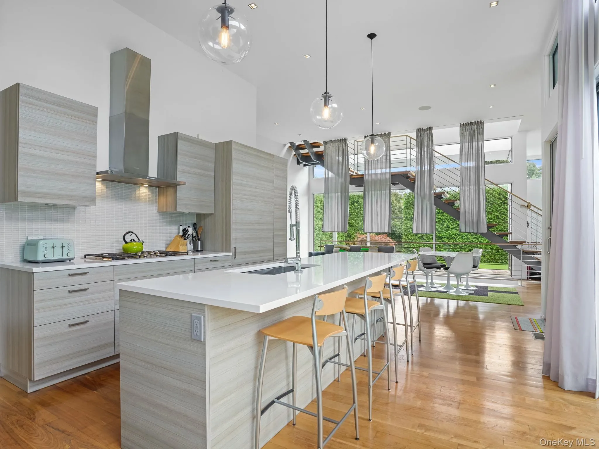 Kitchen featuring healthy amount of natural light, light wood-style flooring, modern cabinets, recessed lighting, and expansive windows Kitchen featuring healthy amount of natural light, light wood-style flooring, modern cabinets, recessed lighting, and expansive windows