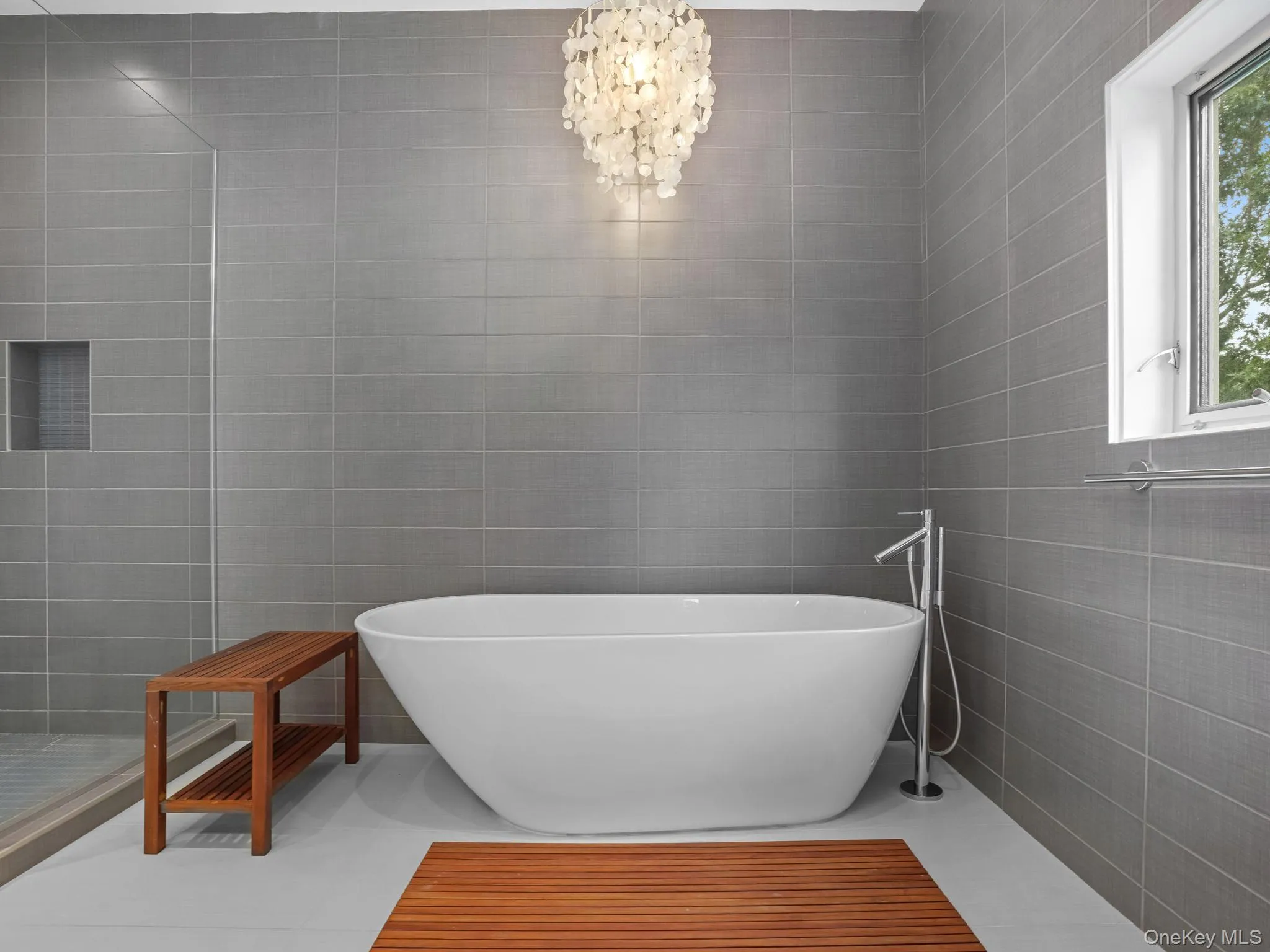 Bathroom with tile walls, a freestanding bath, a walk in shower, and a chandelier Bathroom with tile walls, a freestanding bath, a walk in shower, and a chandelier