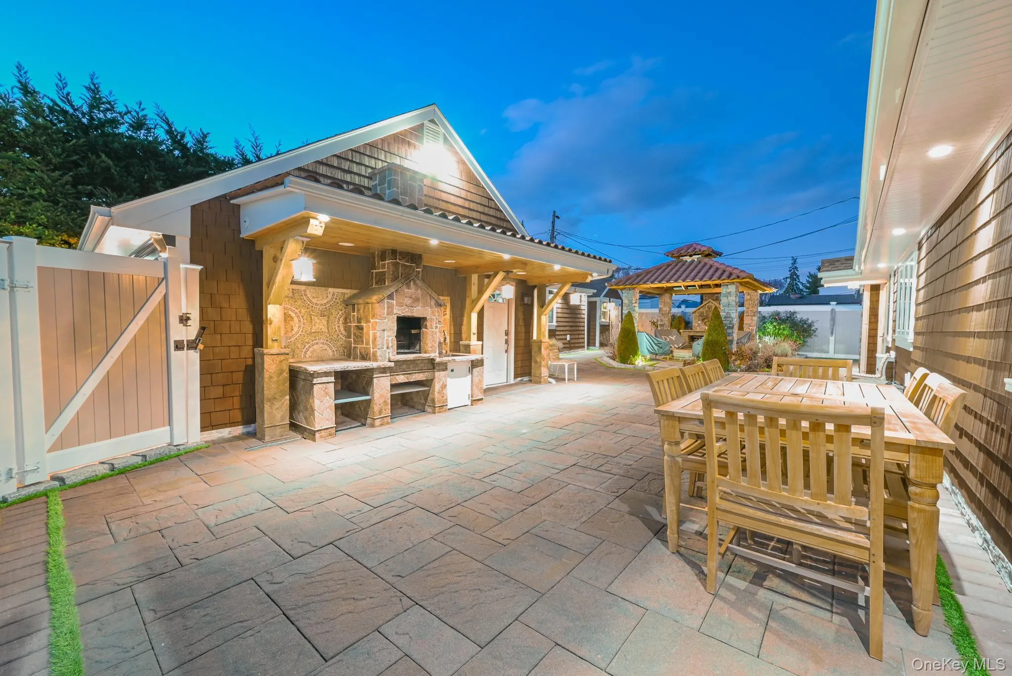 View of patio / terrace with an outdoor stone fireplace, a gate, and outdoor dining space View of patio / terrace with an outdoor stone fireplace, a gate, and outdoor dining space