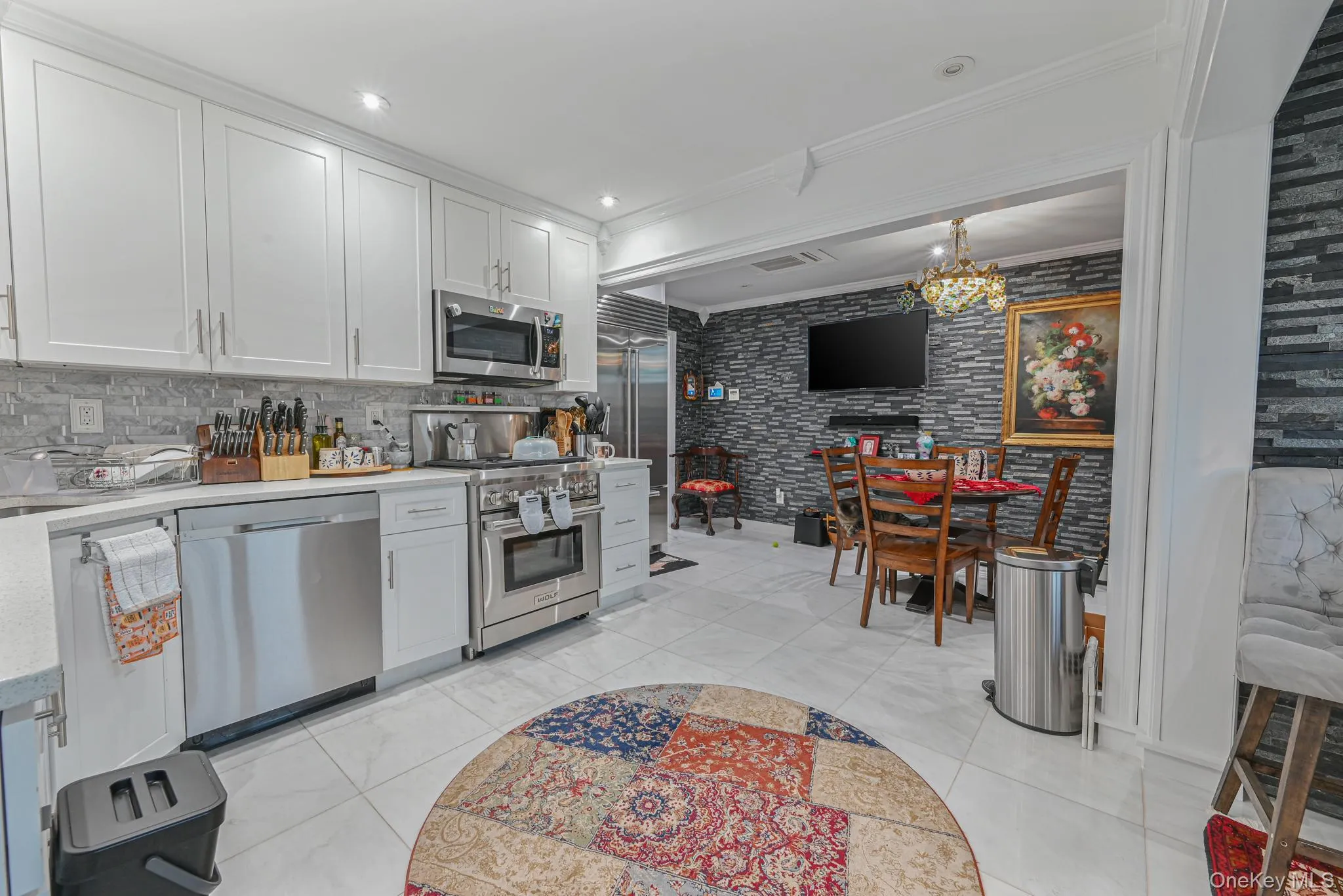 Kitchen with ornamental molding, high quality appliances, white cabinetry, a chandelier, and decorative light fixtures Kitchen with ornamental molding, high quality appliances, white cabinetry, a chandelier, and decorative light fixtures