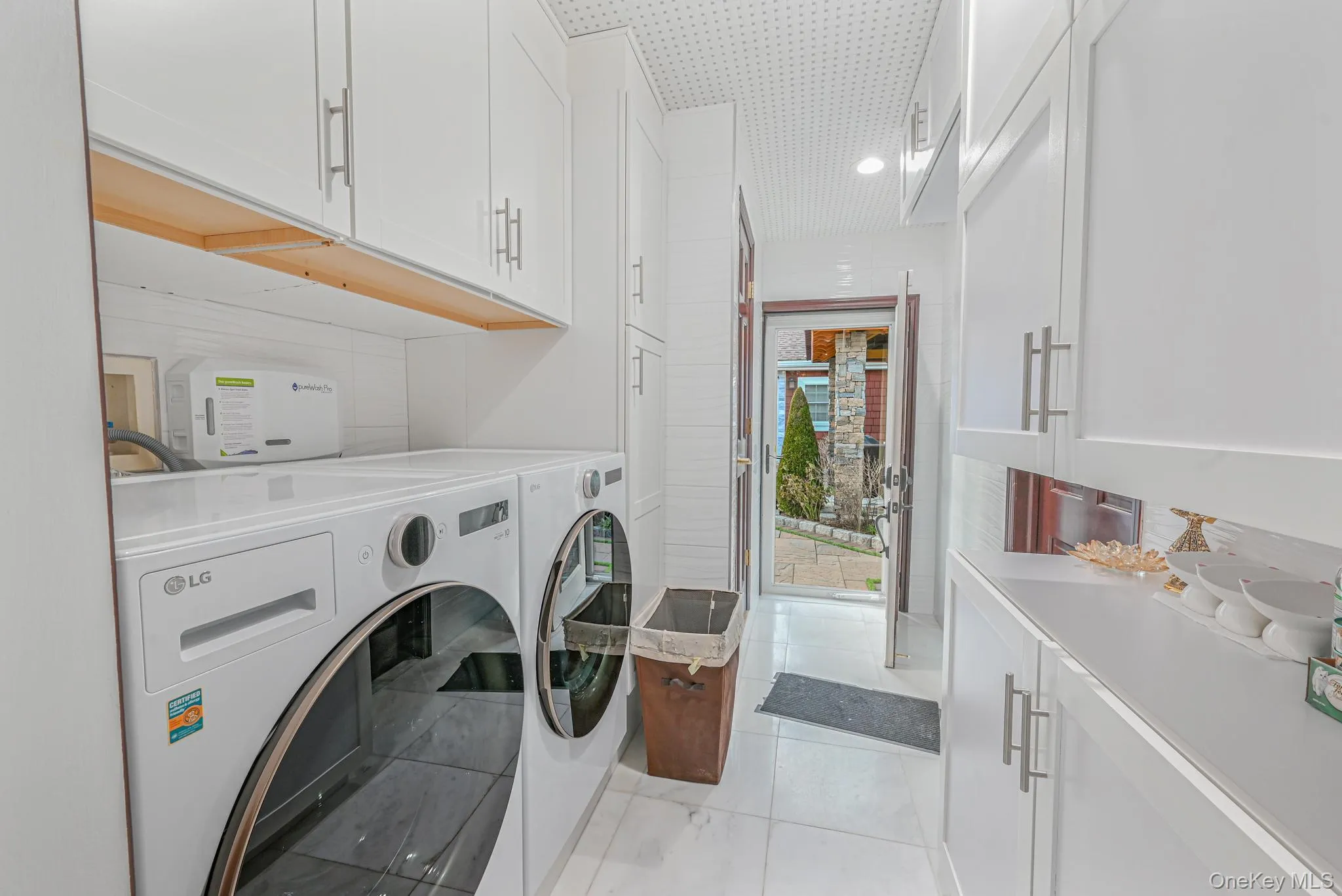 Laundry room with cabinet space, washing machine and dryer, and light tile patterned floors Laundry room with cabinet space, washing machine and dryer, and light tile patterned floors