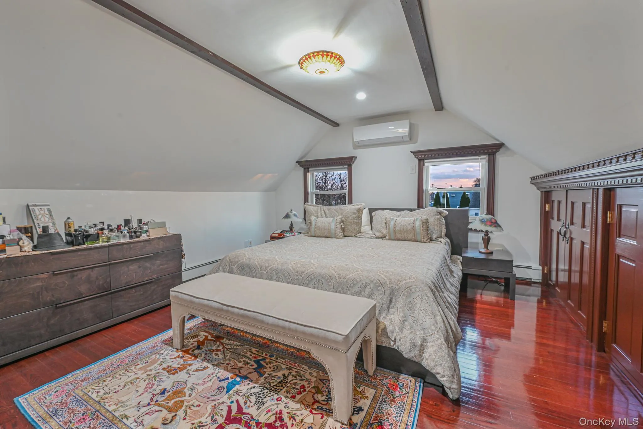 Bedroom featuring dark wood finished floors, baseboard heating, and a wall unit AC Bedroom featuring dark wood finished floors, baseboard heating, and a wall unit AC