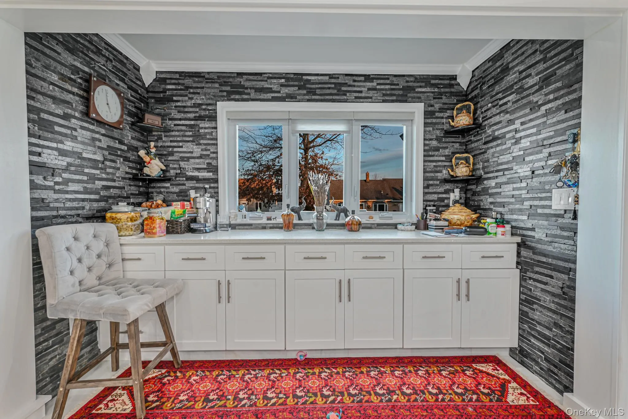 Bar area featuring white cabinetry, crown molding, light stone countertops, and open shelves Bar area featuring white cabinetry, crown molding, light stone countertops, and open shelves