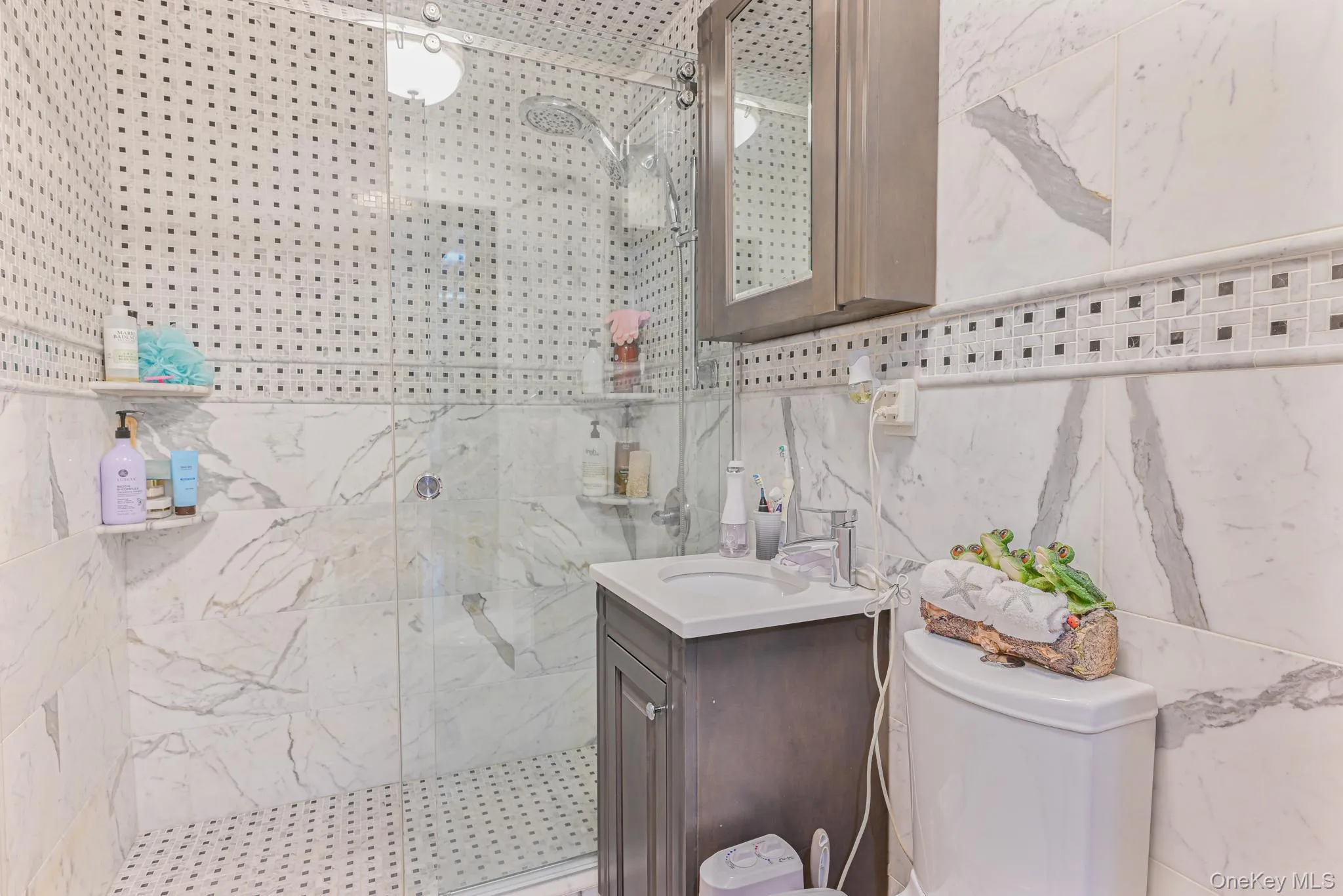 Bathroom with vanity, a marble finish shower, and tile walls Bathroom with vanity, a marble finish shower, and tile walls
