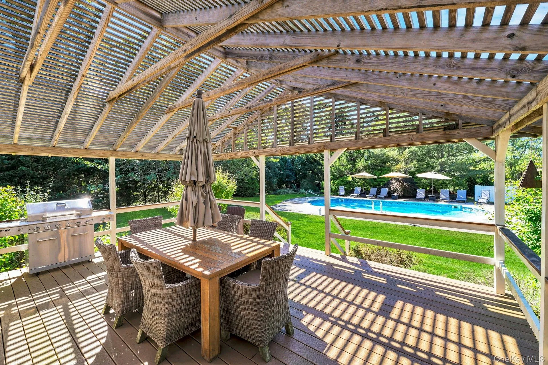 Deck featuring a lawn, outdoor dining area, an outdoor pool, and grilling area Deck featuring a lawn, outdoor dining area, an outdoor pool, and grilling area