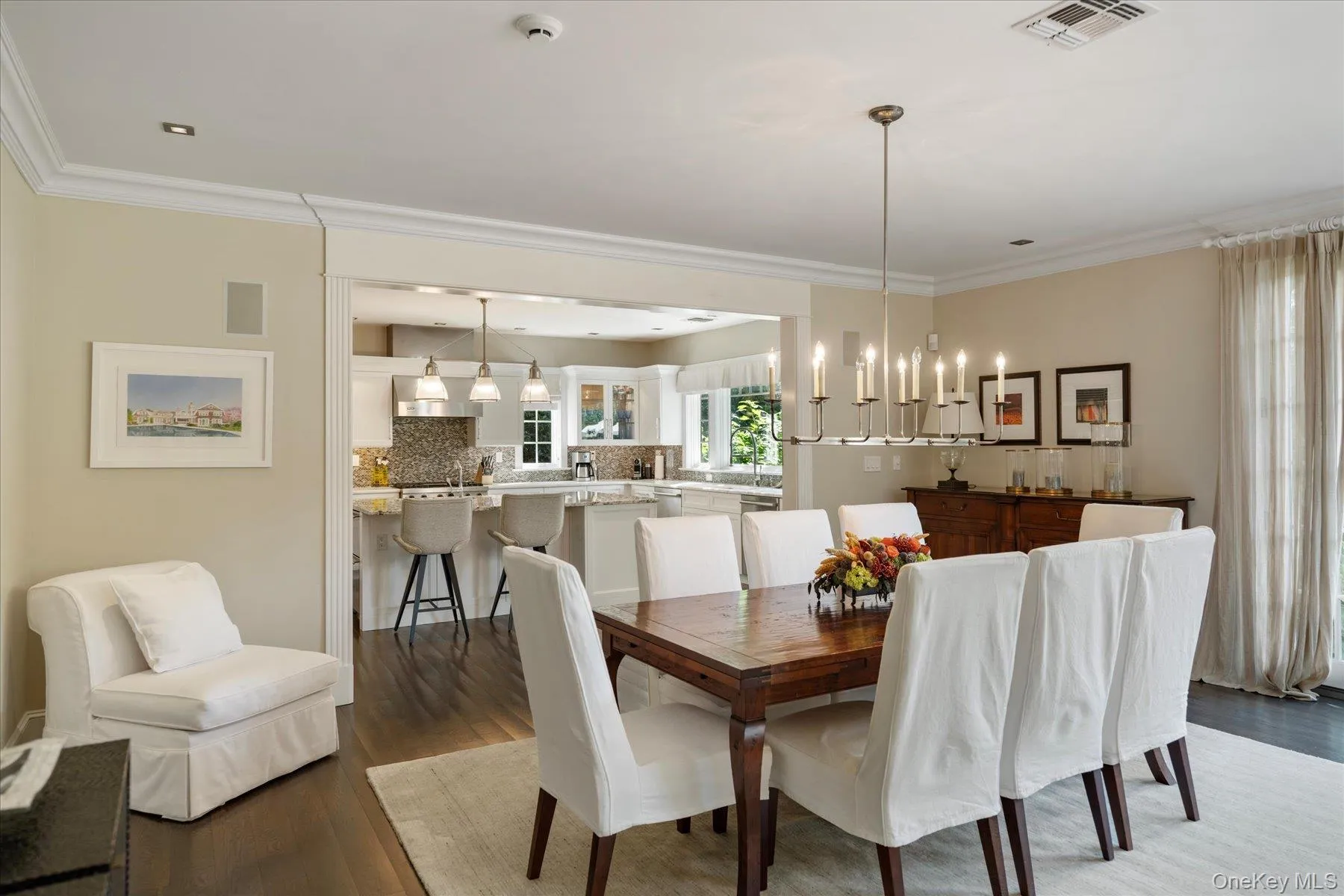 Dining space with dark wood-style flooring, ornamental molding, and a chandelier Dining space with dark wood-style flooring, ornamental molding, and a chandelier