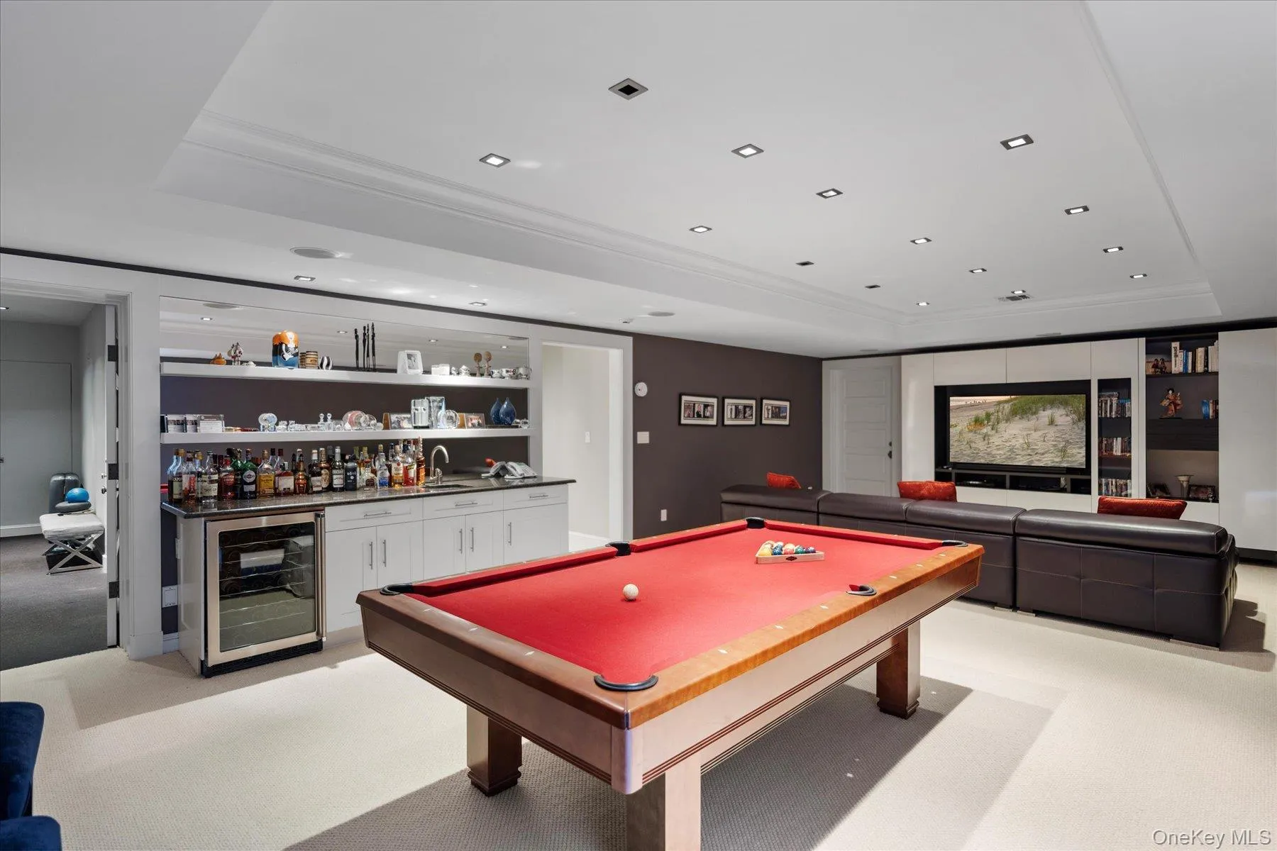 Rec room with a tray ceiling, light colored carpet, wet bar, beverage cooler, and recessed lighting Rec room with a tray ceiling, light colored carpet, wet bar, beverage cooler, and recessed lighting