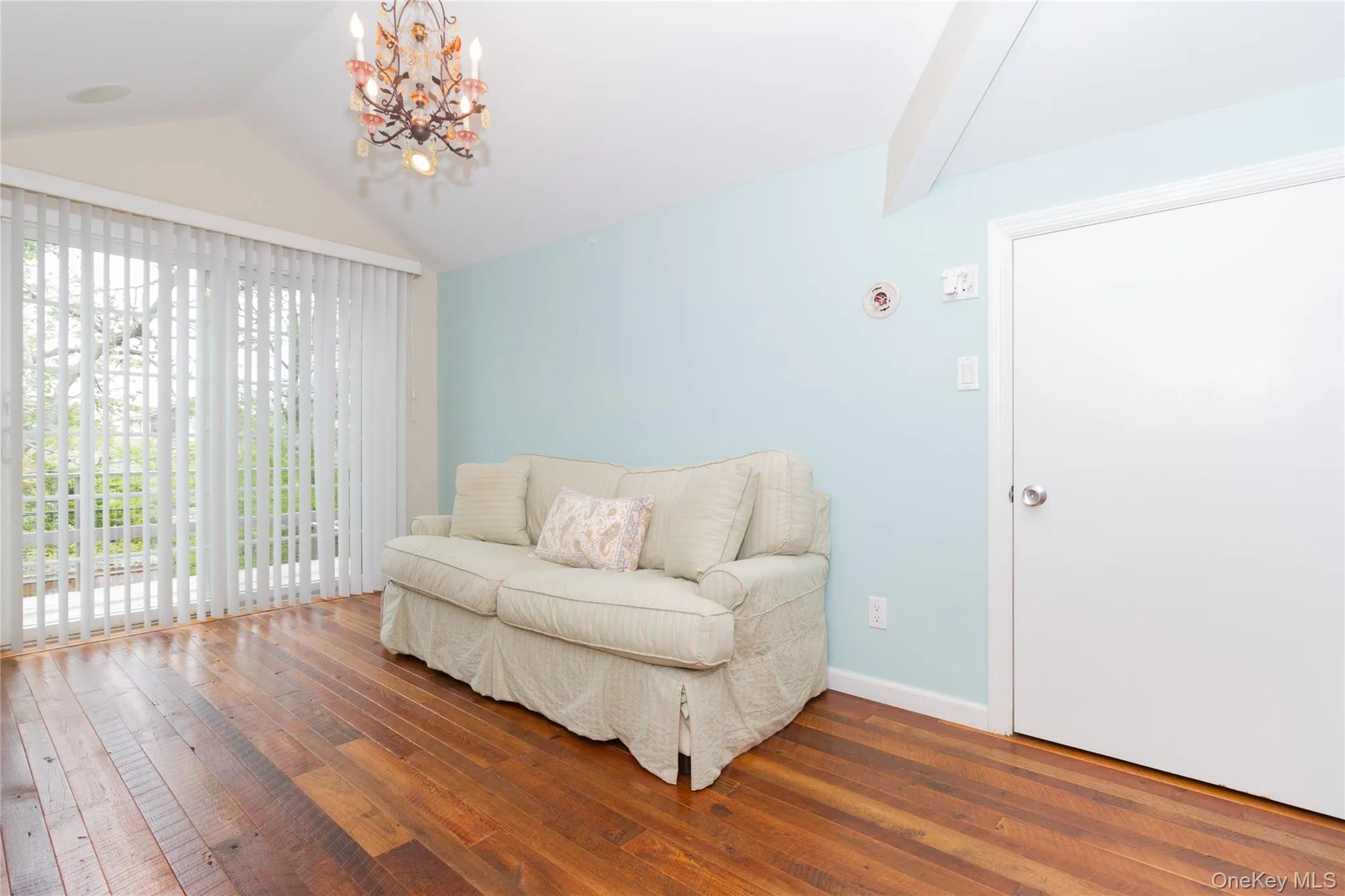 Living area with a chandelier, lofted ceiling, and hardwood / wood-style floors Living area with a chandelier, lofted ceiling, and hardwood / wood-style floors