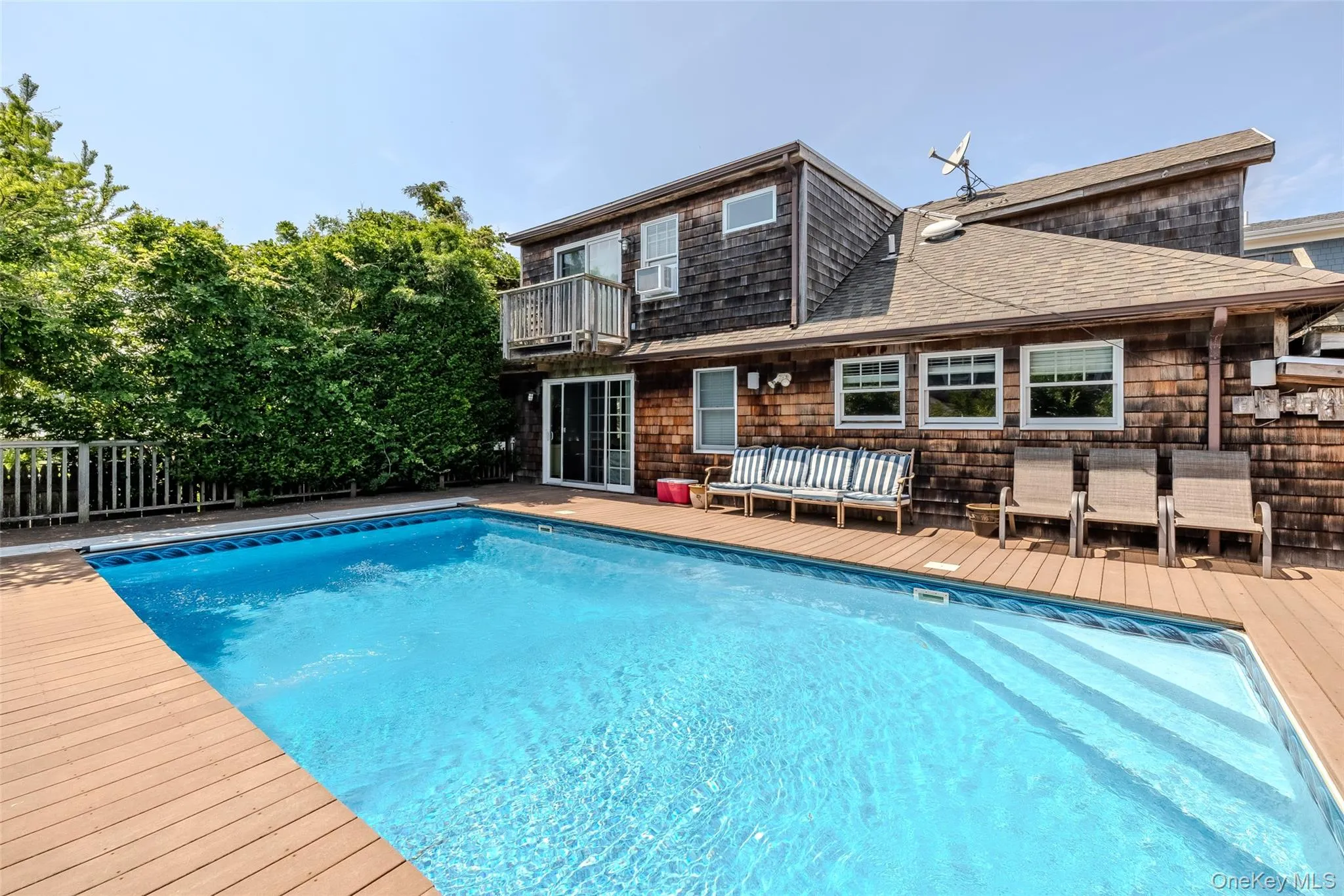 Outdoor pool with a wooden deck, an outdoor living space, and a balcony Outdoor pool with a wooden deck, an outdoor living space, and a balcony