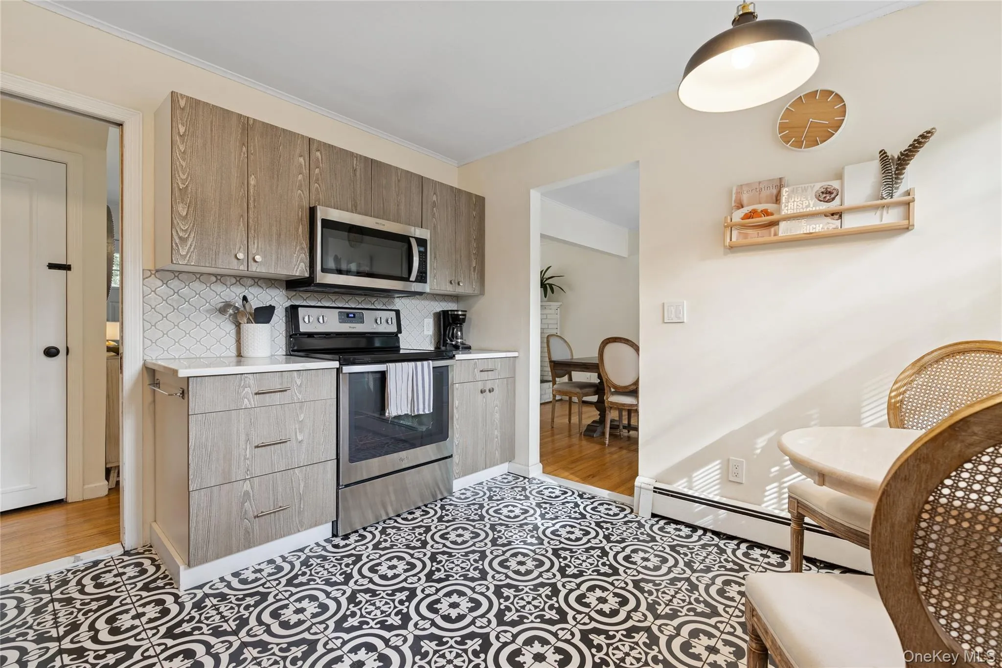 Kitchen featuring stainless steel appliances, light countertops, baseboard heating, backsplash, and crown molding Kitchen featuring stainless steel appliances, light countertops, baseboard heating, backsplash, and crown molding