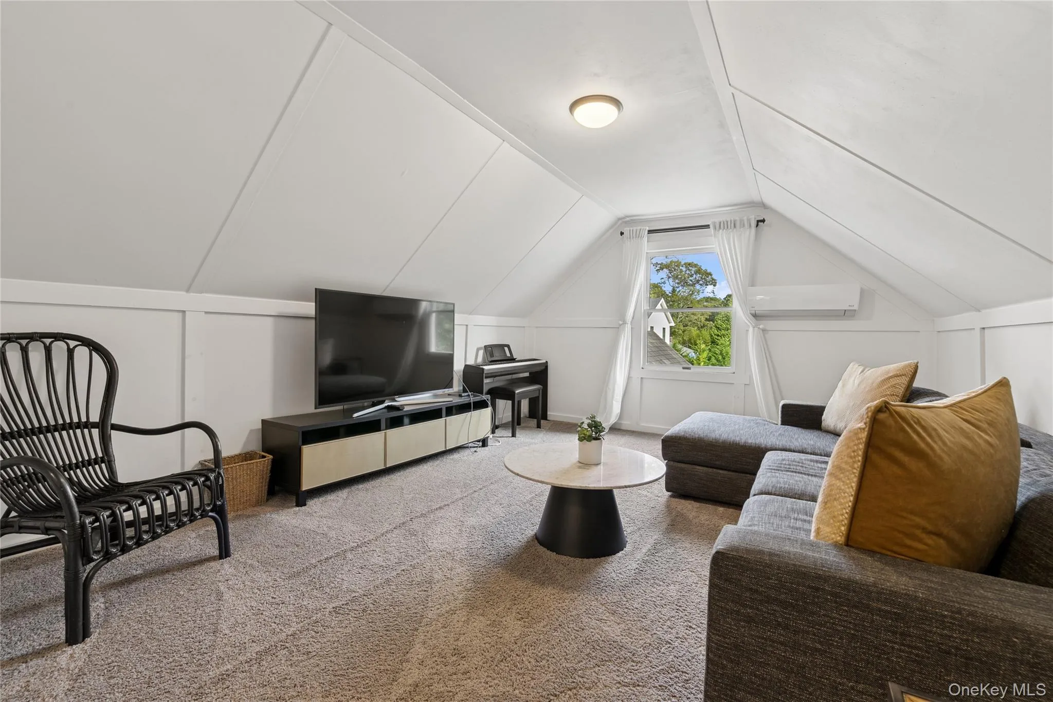 Living area featuring lofted ceiling, carpet flooring, and a wall mounted air conditioner Living area featuring lofted ceiling, carpet flooring, and a wall mounted air conditioner