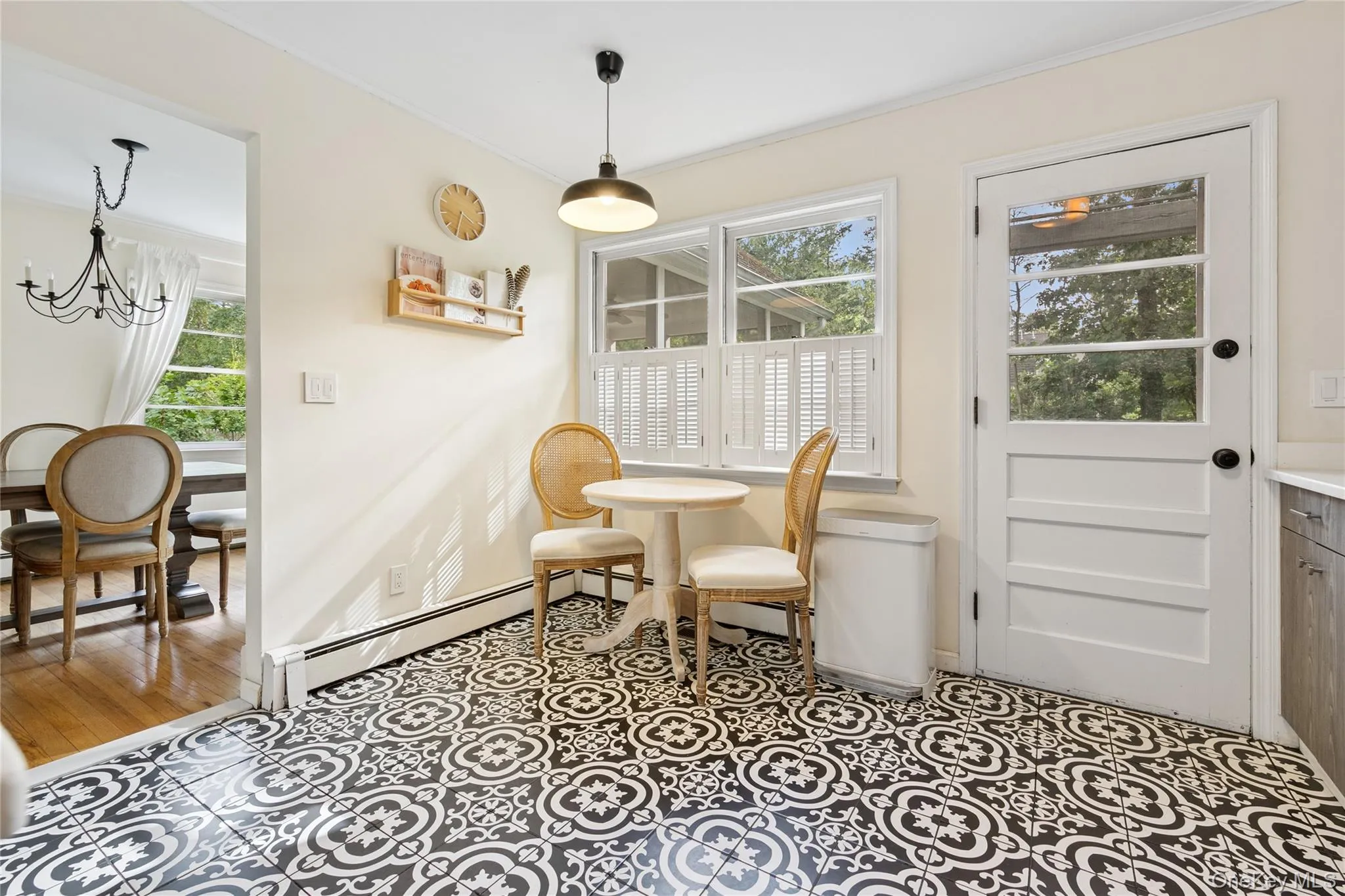Dining space featuring healthy amount of natural light, light tile patterned floors, ornamental molding, a chandelier, and a baseboard heating unit Dining space featuring healthy amount of natural light, light tile patterned floors, ornamental molding, a chandelier, and a baseboard heating unit