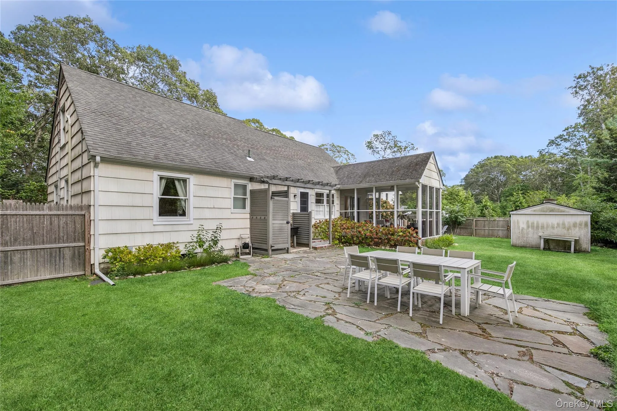 Rear view of house featuring a patio area, a sunroom, a fenced backyard, roof with shingles, and a storage shed Rear view of house featuring a patio area, a sunroom, a fenced backyard, roof with shingles, and a storage shed