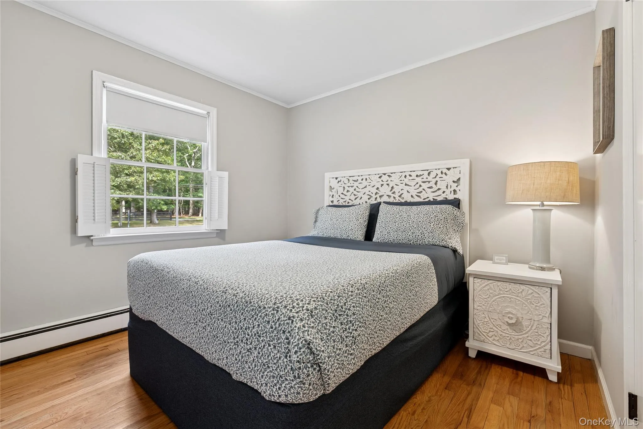 Bedroom with crown molding, a baseboard radiator, and wood finished floors Bedroom with crown molding, a baseboard radiator, and wood finished floors