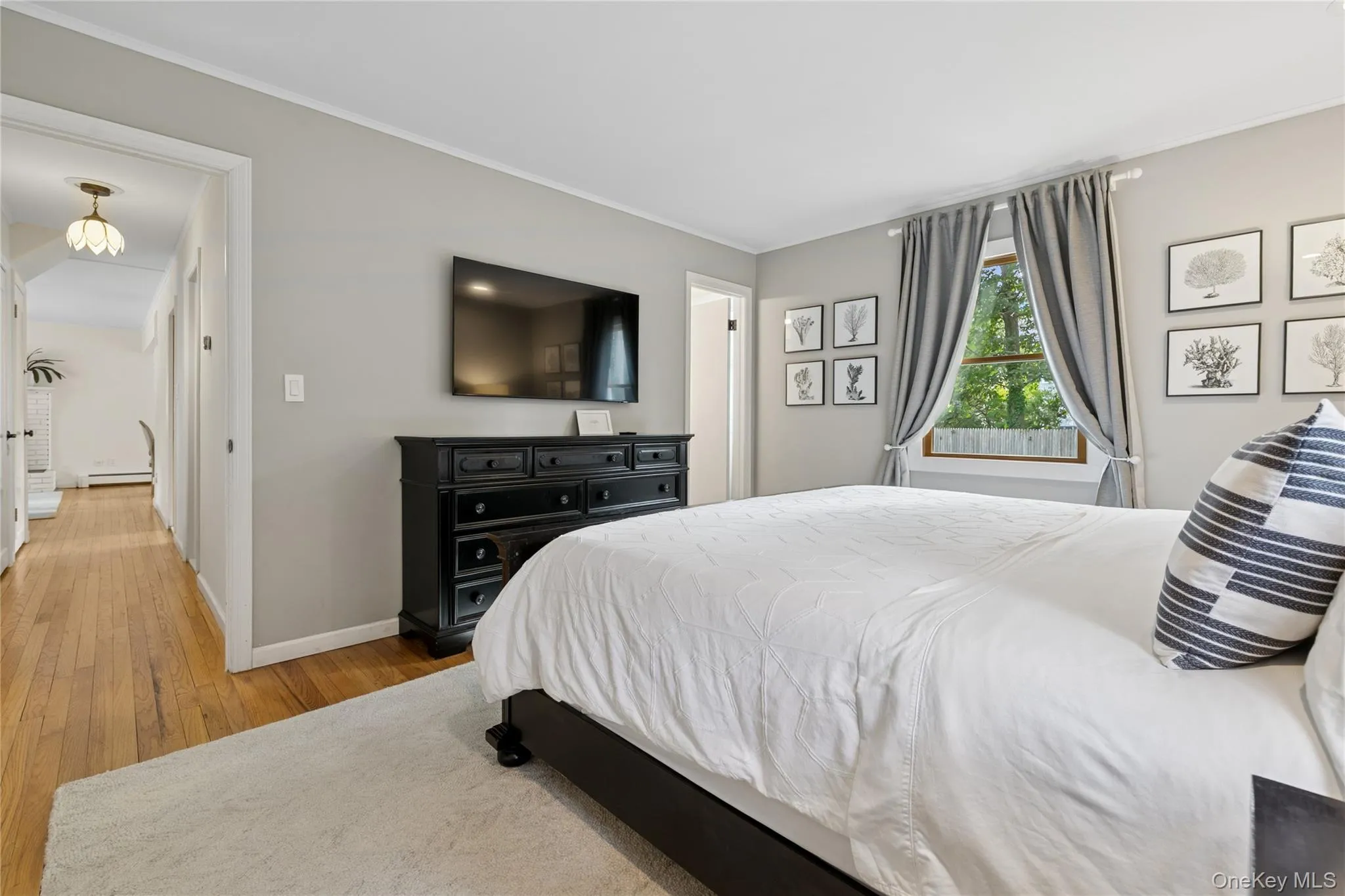 Bedroom featuring hardwood / wood-style flooring, a baseboard radiator, and crown molding Bedroom featuring hardwood / wood-style flooring, a baseboard radiator, and crown molding