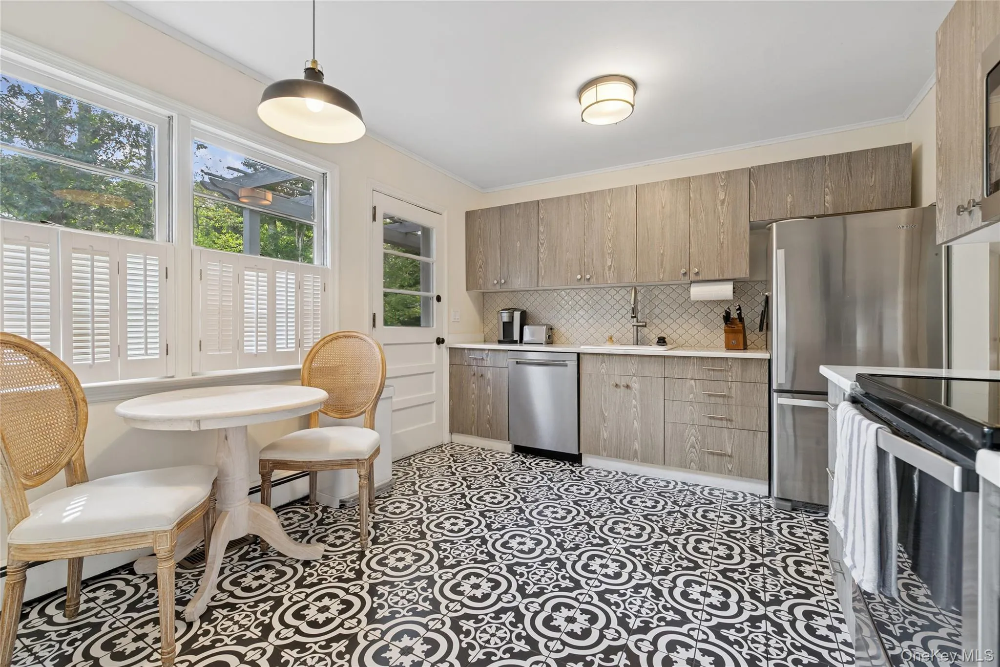 Kitchen with stainless steel appliances, tasteful backsplash, hanging light fixtures, crown molding, and a baseboard heating unit Kitchen with stainless steel appliances, tasteful backsplash, hanging light fixtures, crown molding, and a baseboard heating unit