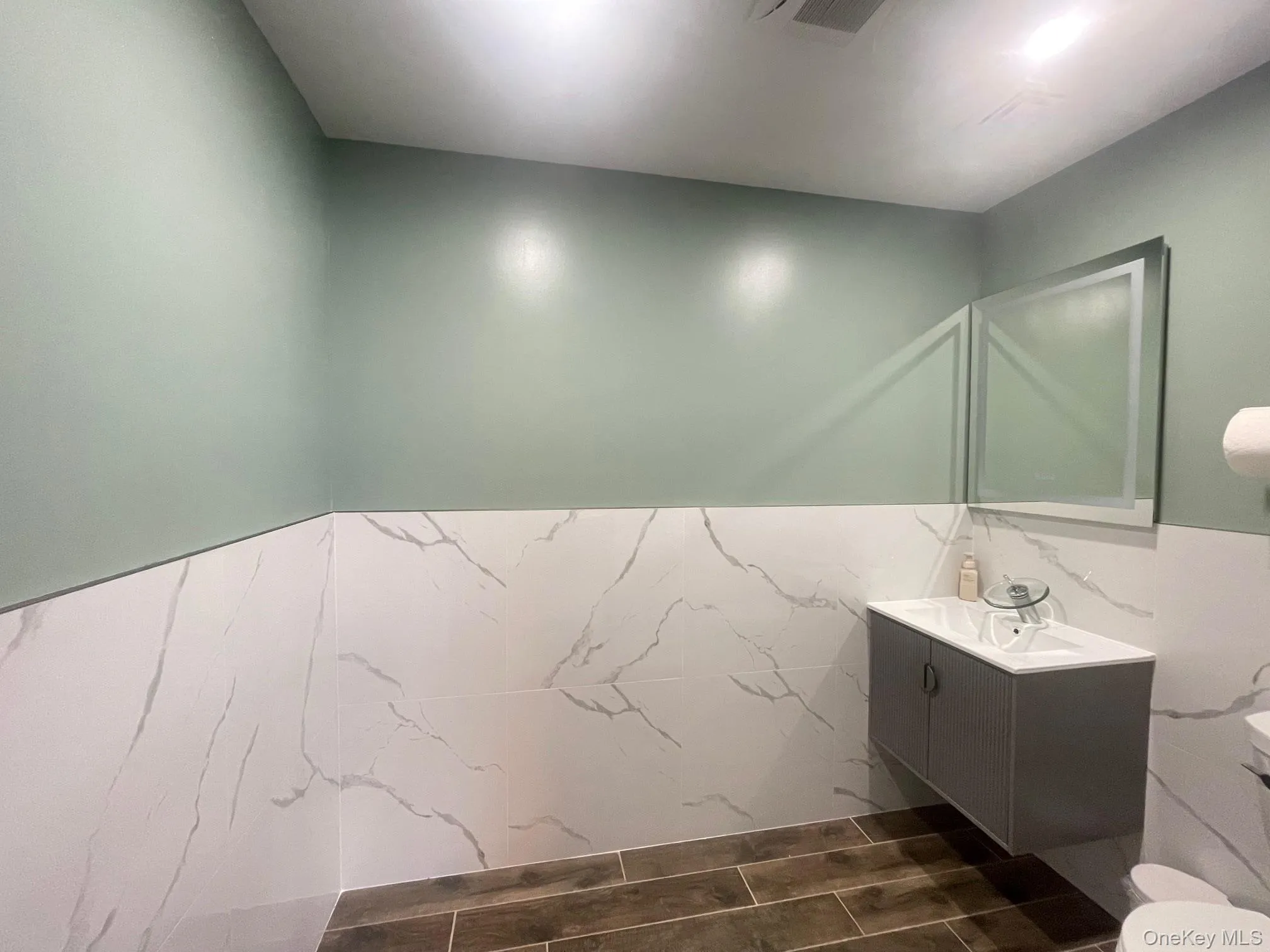 Bathroom featuring vanity, tile walls, and a wainscoted wall Bathroom featuring vanity, tile walls, and a wainscoted wall