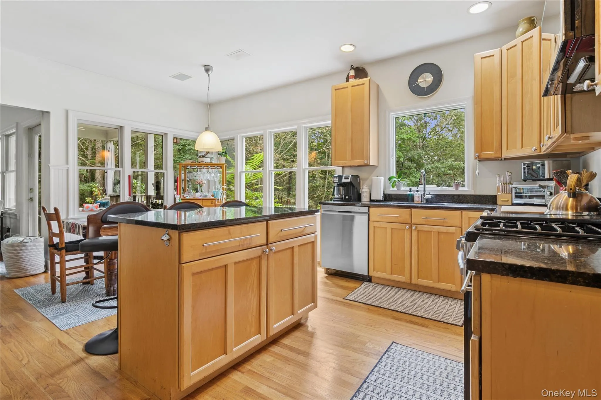 Kitchen with a kitchen island, appliances with stainless steel finishes, light wood-style floors, light brown cabinetry, and a breakfast bar area Kitchen with a kitchen island, appliances with stainless steel finishes, light wood-style floors, light brown cabinetry, and a breakfast bar area