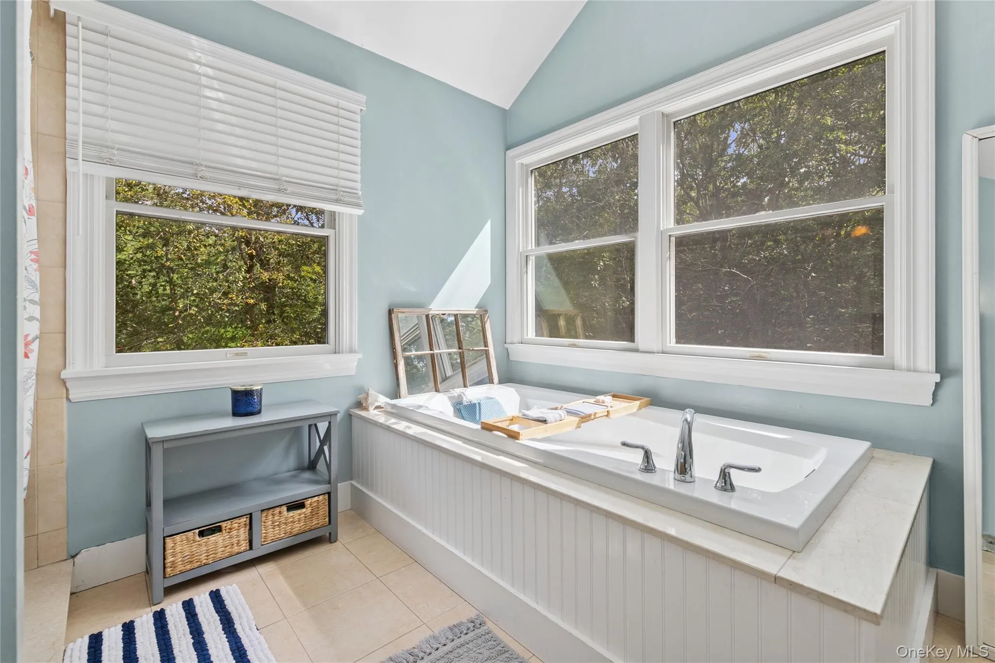 Full bathroom featuring a bath, lofted ceiling, and light tile patterned floors Full bathroom featuring a bath, lofted ceiling, and light tile patterned floors