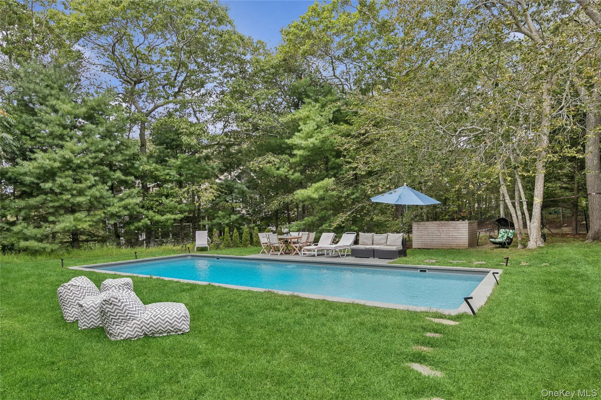 Outdoor pool featuring view of wooded area and a patio area Outdoor pool featuring view of wooded area and a patio area