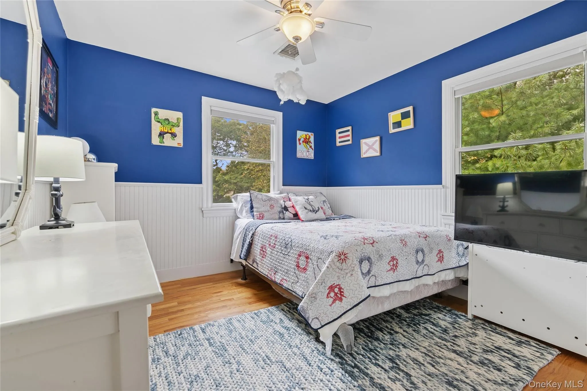 Bedroom with light wood-style flooring, wainscoting, and a ceiling fan Bedroom with light wood-style flooring, wainscoting, and a ceiling fan