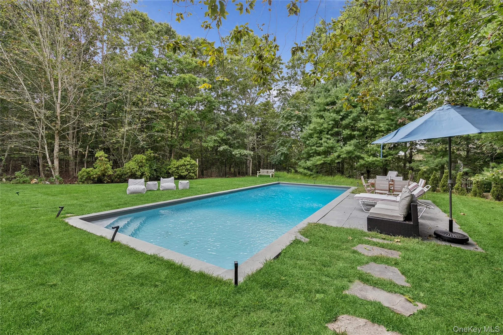 Outdoor pool with a lawn and a patio area Outdoor pool with a lawn and a patio area