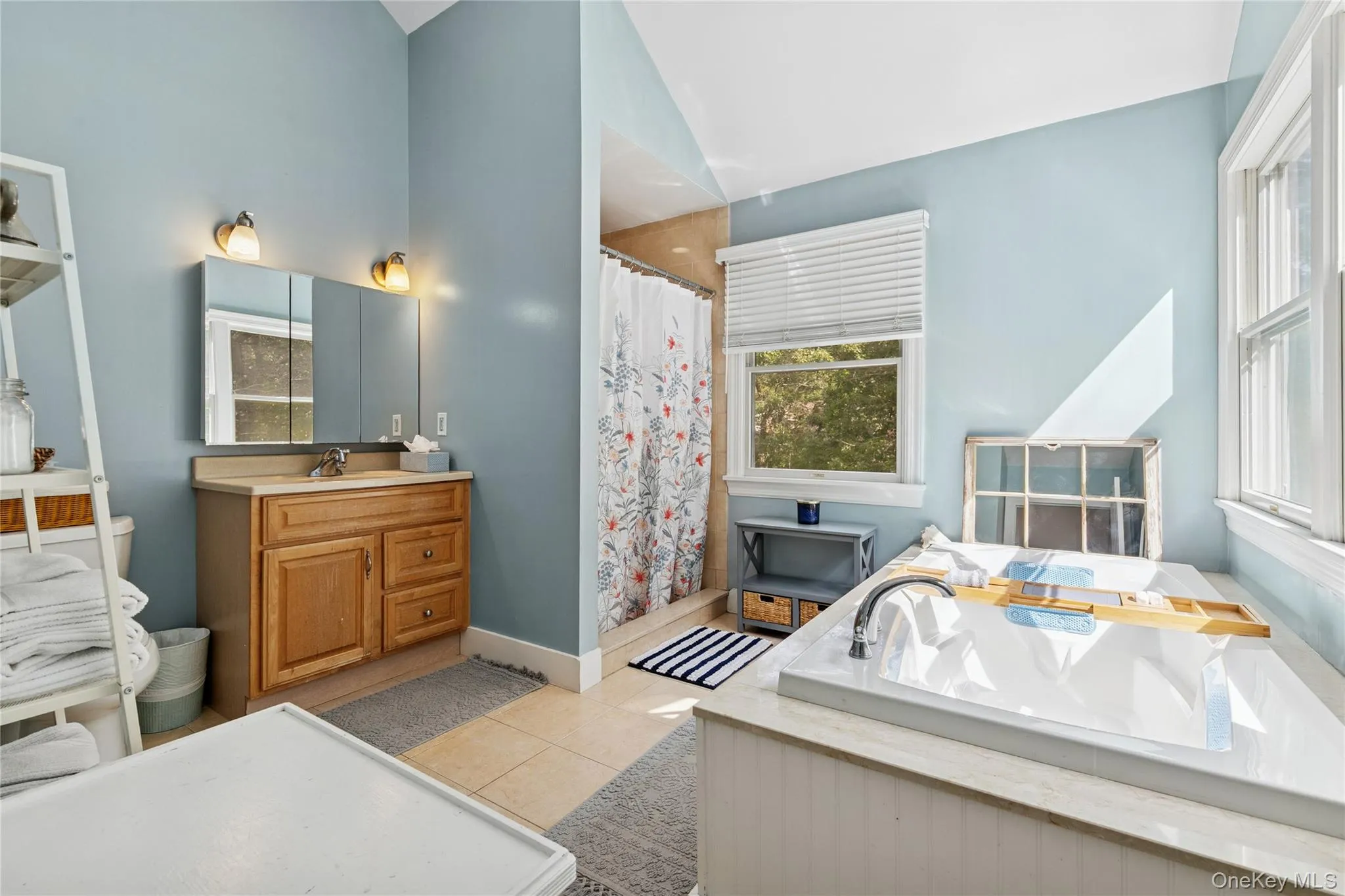 Full bath with light tile patterned floors, vanity, a stall shower, and a garden tub Full bath with light tile patterned floors, vanity, a stall shower, and a garden tub