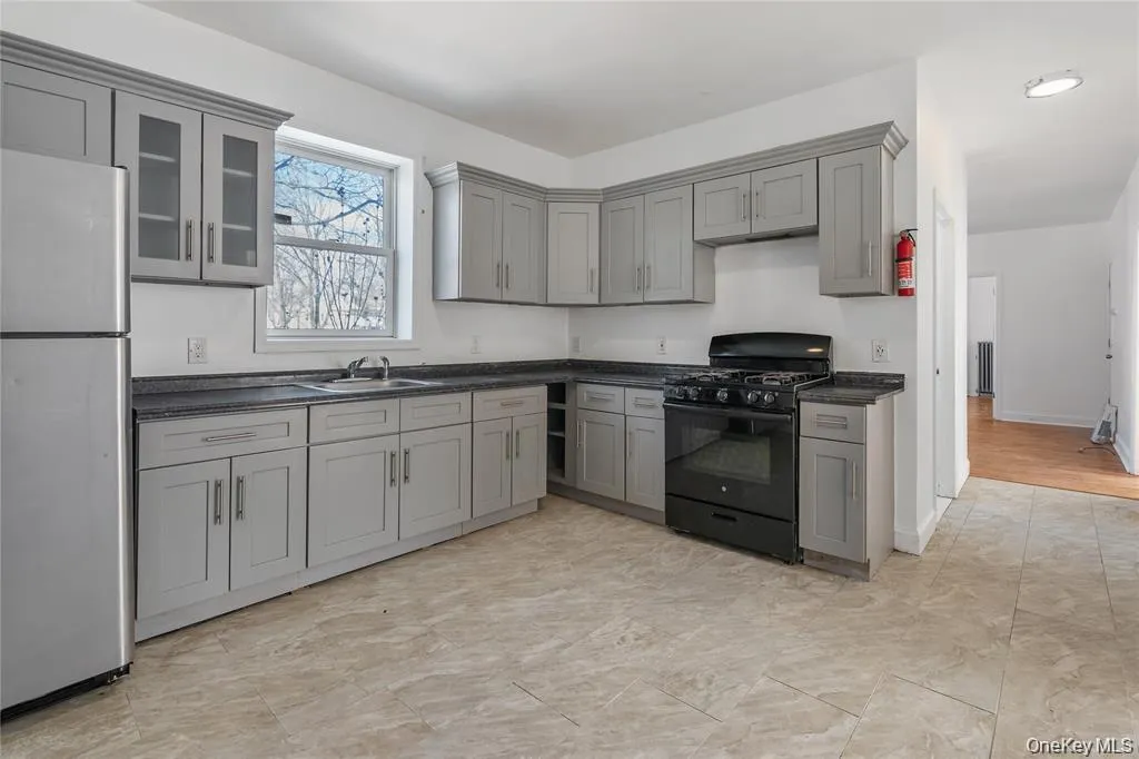 Kitchen with gray cabinets, black gas stove, freestanding refrigerator, and glass insert cabinets Kitchen with gray cabinets, black gas stove, freestanding refrigerator, and glass insert cabinets