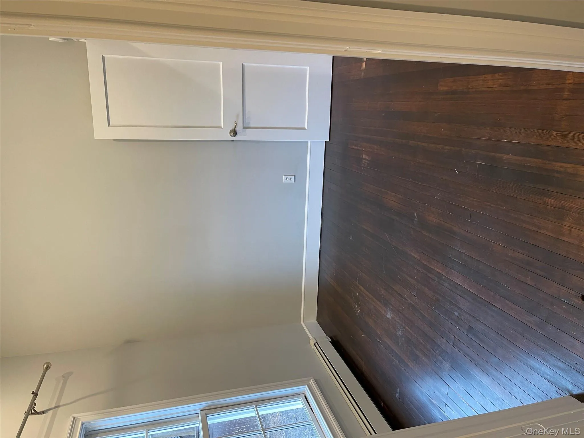 Unfurnished room featuring baseboard heating and dark wood-style floors Unfurnished room featuring baseboard heating and dark wood-style floors