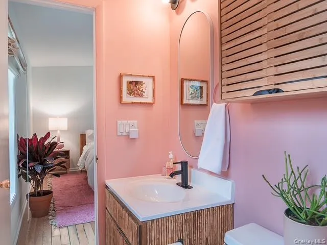 Half bathroom with vanity, light wood-style flooring, and ensuite bath Half bathroom with vanity, light wood-style flooring, and ensuite bath