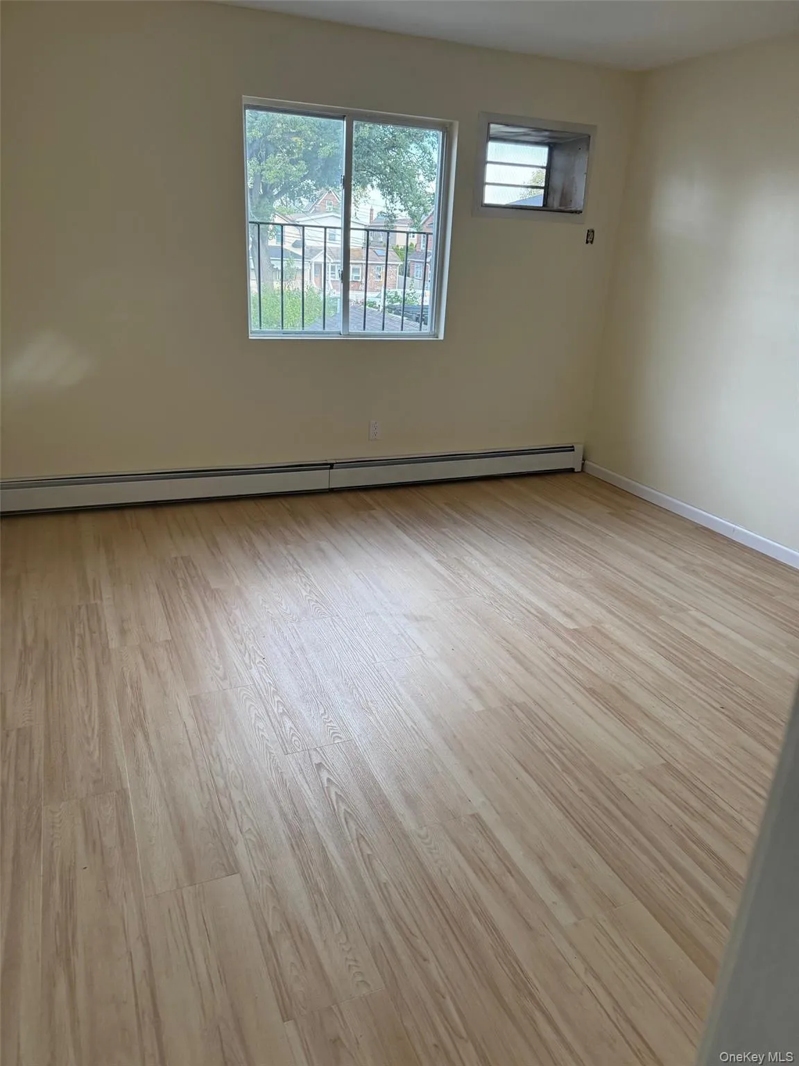 Empty room featuring light wood-style flooring and a baseboard heating unit Empty room featuring light wood-style flooring and a baseboard heating unit