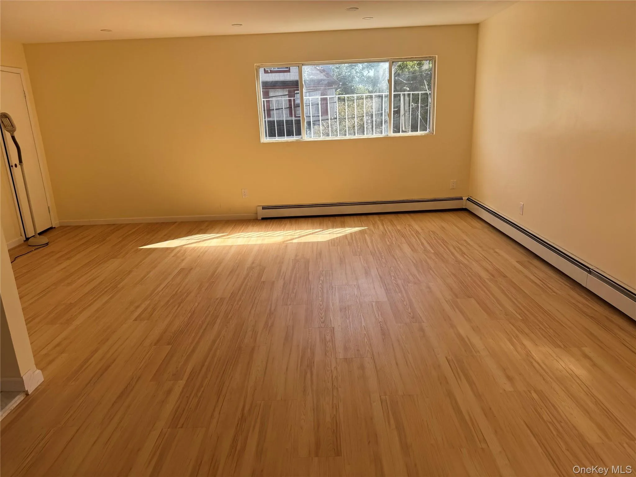 Unfurnished room featuring light wood-style flooring and baseboard heating Unfurnished room featuring light wood-style flooring and baseboard heating