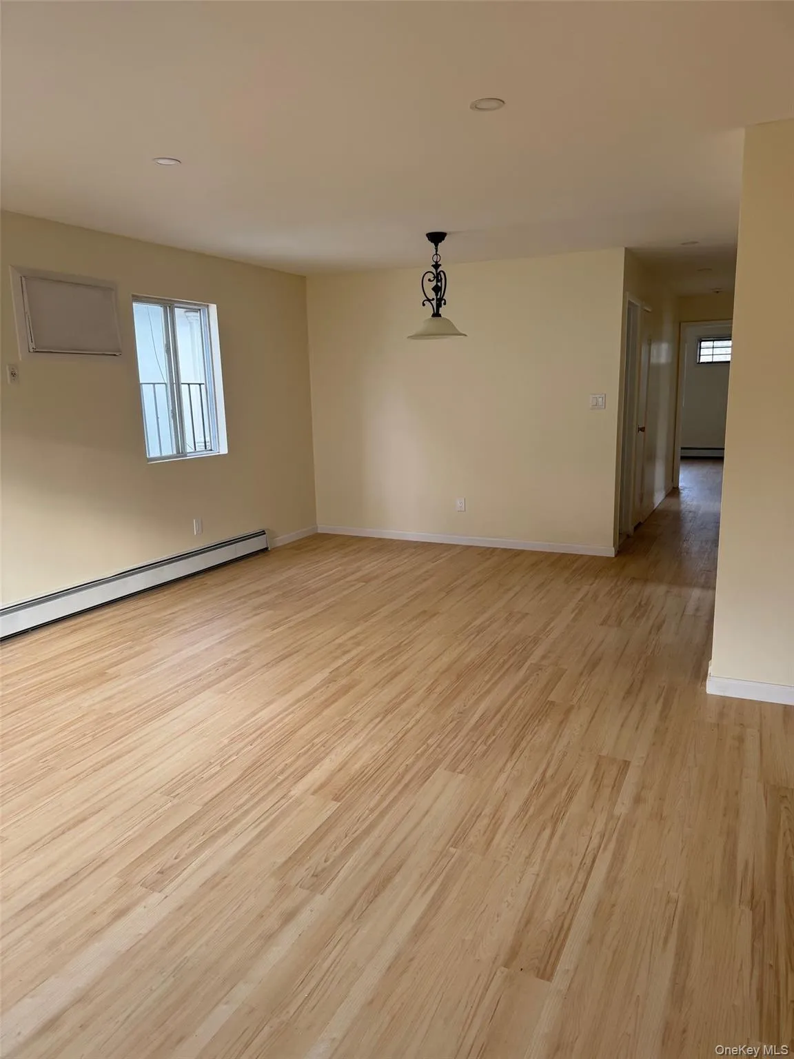 Empty room with a baseboard heating unit, light wood finished floors, and recessed lighting Empty room with a baseboard heating unit, light wood finished floors, and recessed lighting